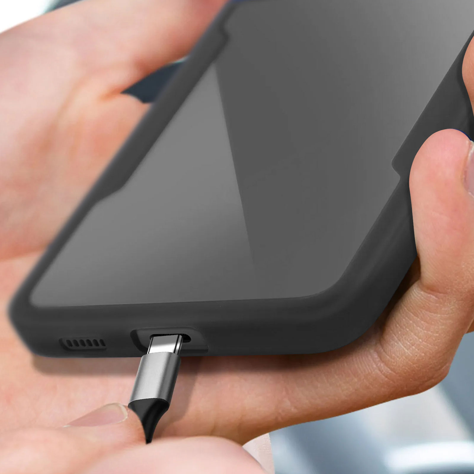 Eine Hand, die ein schwarzes Telefon mit eingestecktem USB-C-Kabel hält.
