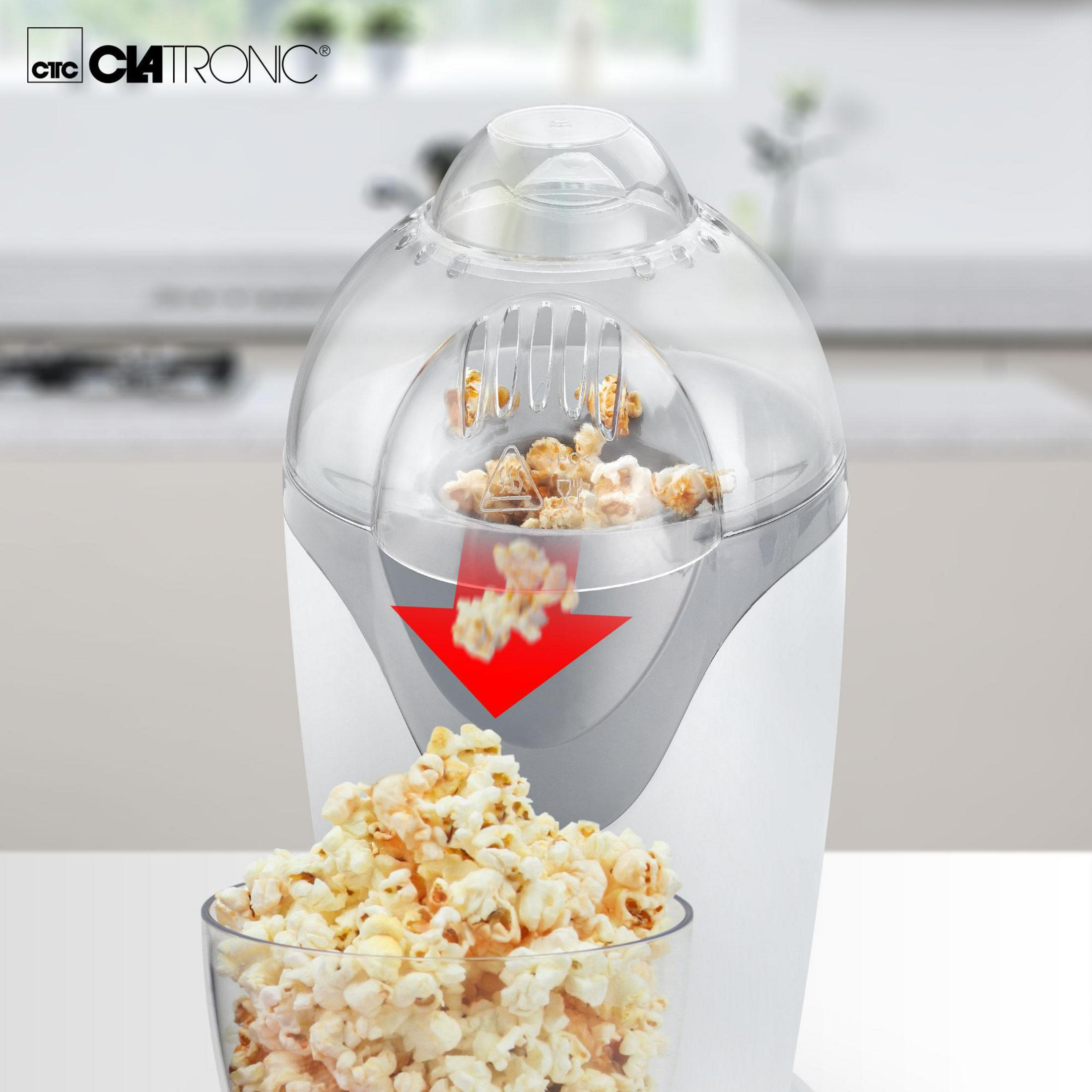 Popcornmaschine mit Popcorn und einer Glasschüssel mit Popcorn. Roter Pfeil zeigt die Richtung an.