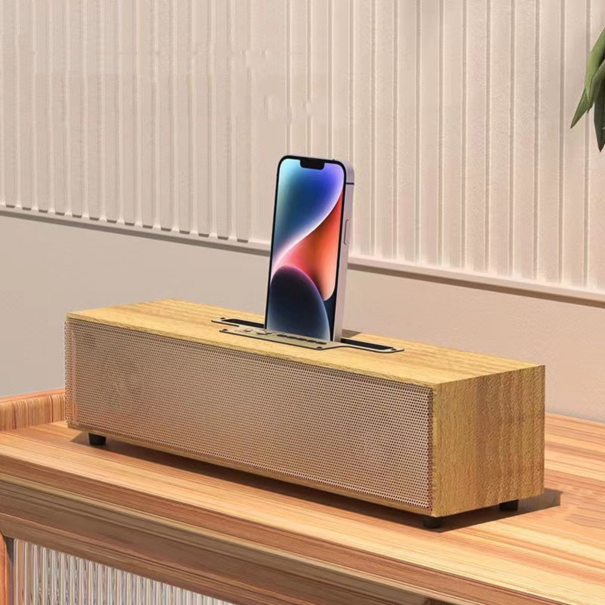 Soundbar aus Holz mit einem Telefon, das in einen Schlitz oben eingesetzt ist. Der Lautsprecher steht auf einem Tisch.