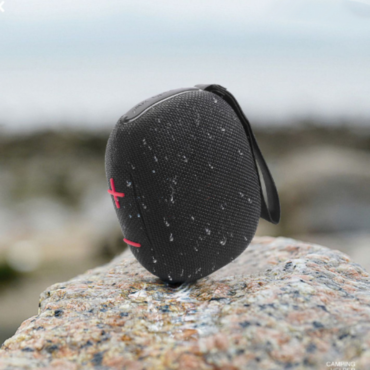 Schwarzer und roter Lautsprecher auf einem Felsen. Der Hintergrund ist unscharf.
