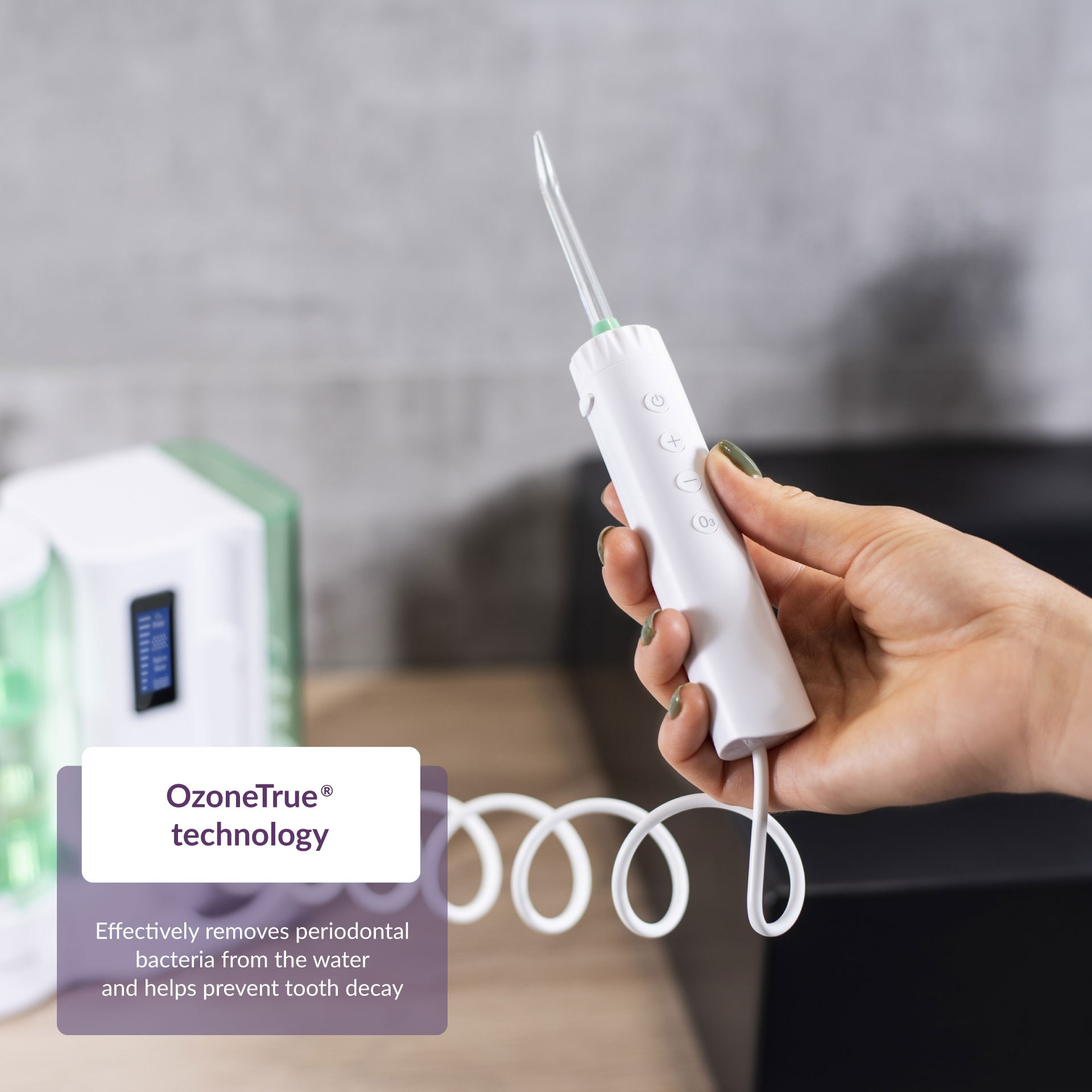 Una mano che tiene un irrigatore orale bianco con tubo bianco. Il testo dice 'OzoneTrue technology'.