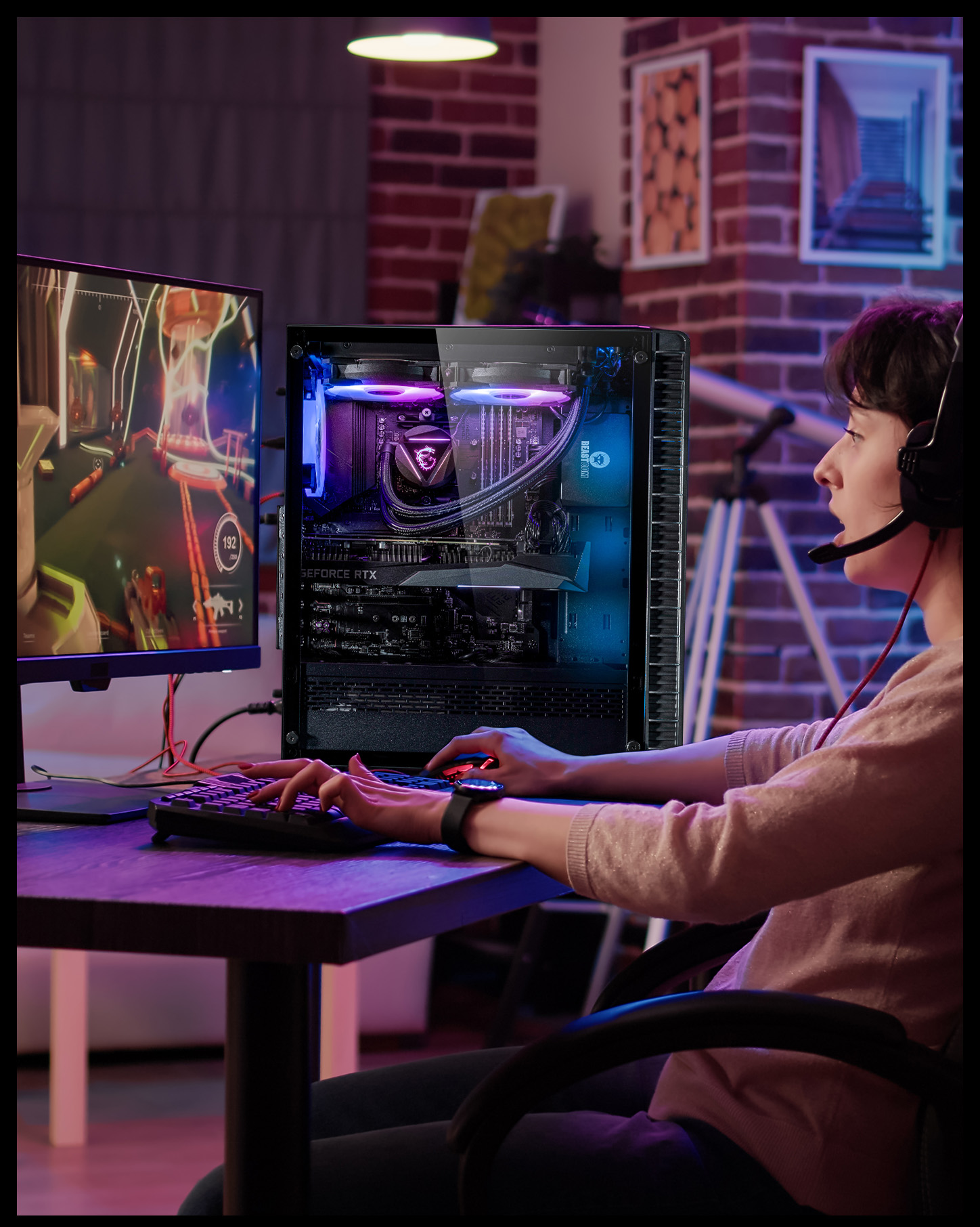 Eine Frau spielt an einem Schreibtisch mit einem PC. Das PC-Gehäuse ist offen. Der Monitor zeigt eine Spielszene.