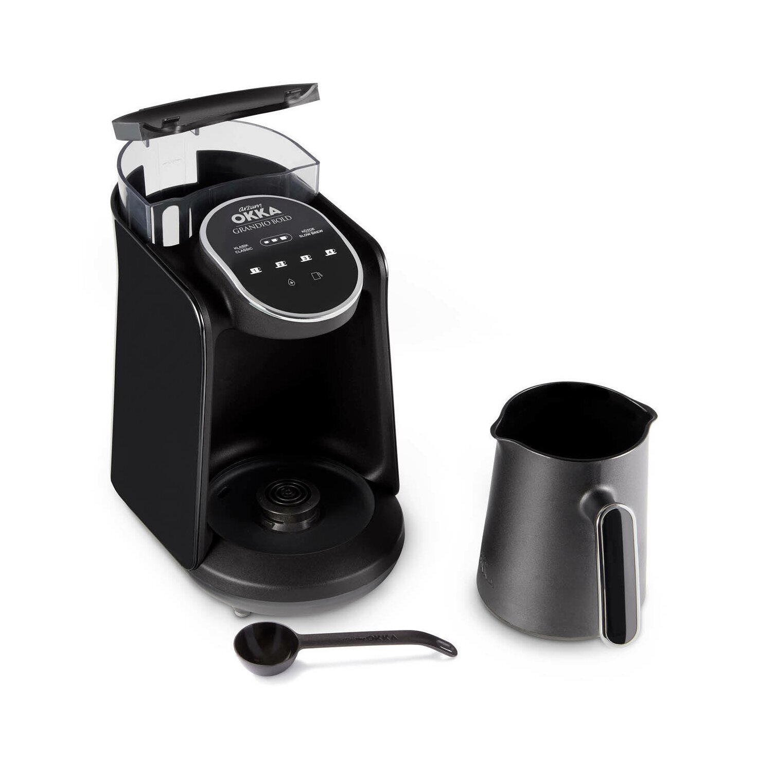 Schwarze Kaffeemaschine, ein Krug und ein Löffel auf weißer Oberfläche.