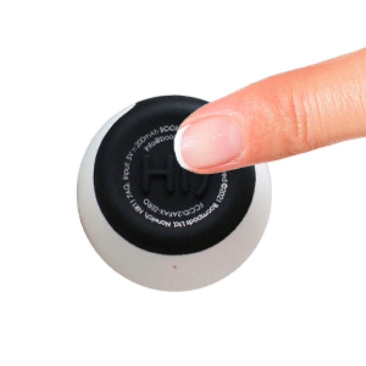 Palec naciska przycisk na spodzie biało-czarnego głośnika.