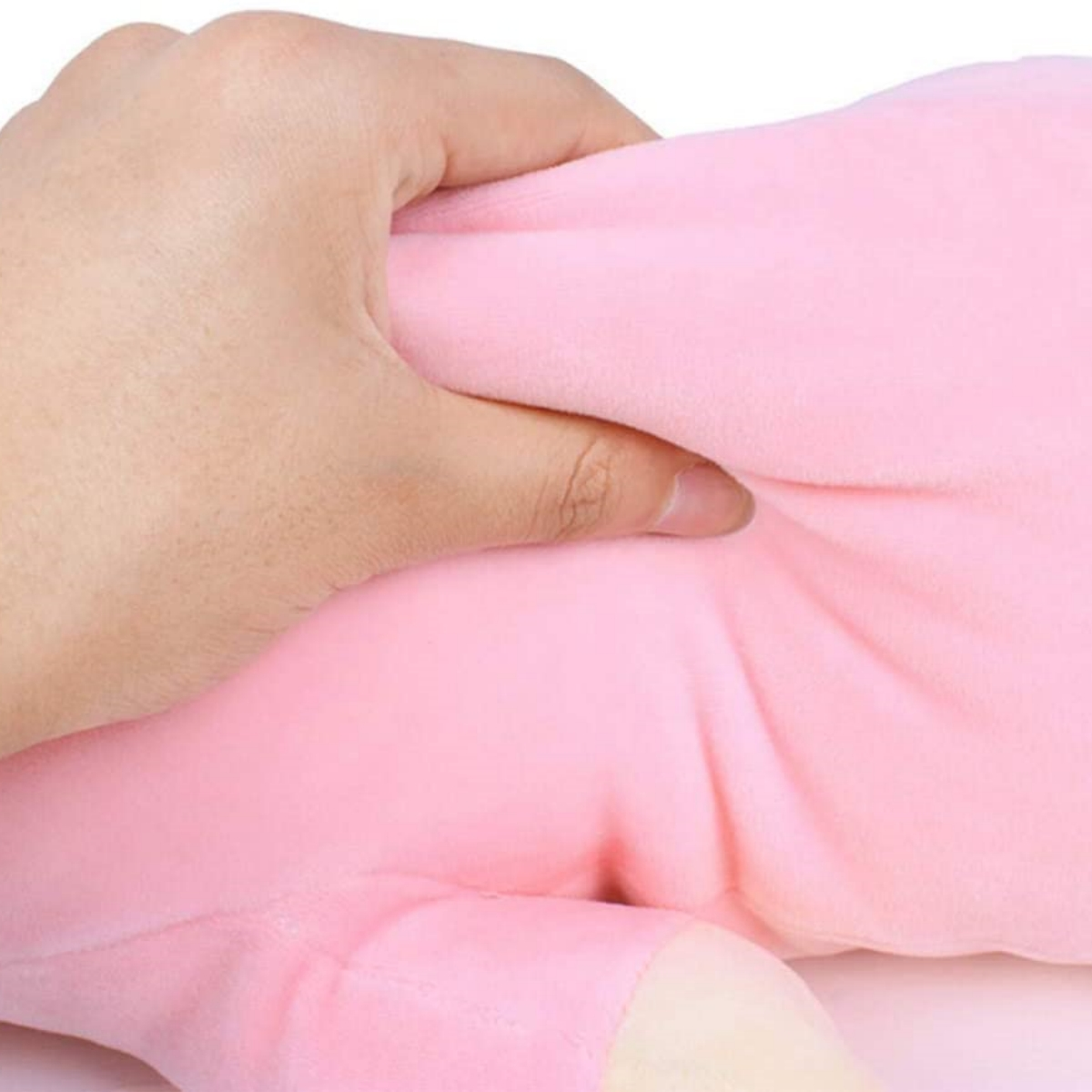 Eine Hand drückt ein weiches, rosa Plüschtier zusammen. Fokus auf die Textur des Spielzeugs und die Hand.