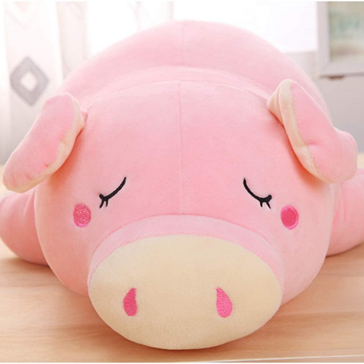 Rosa Plüschschwein-Spielzeug, das mit geschlossenen Augen und rosa Wangen liegt.