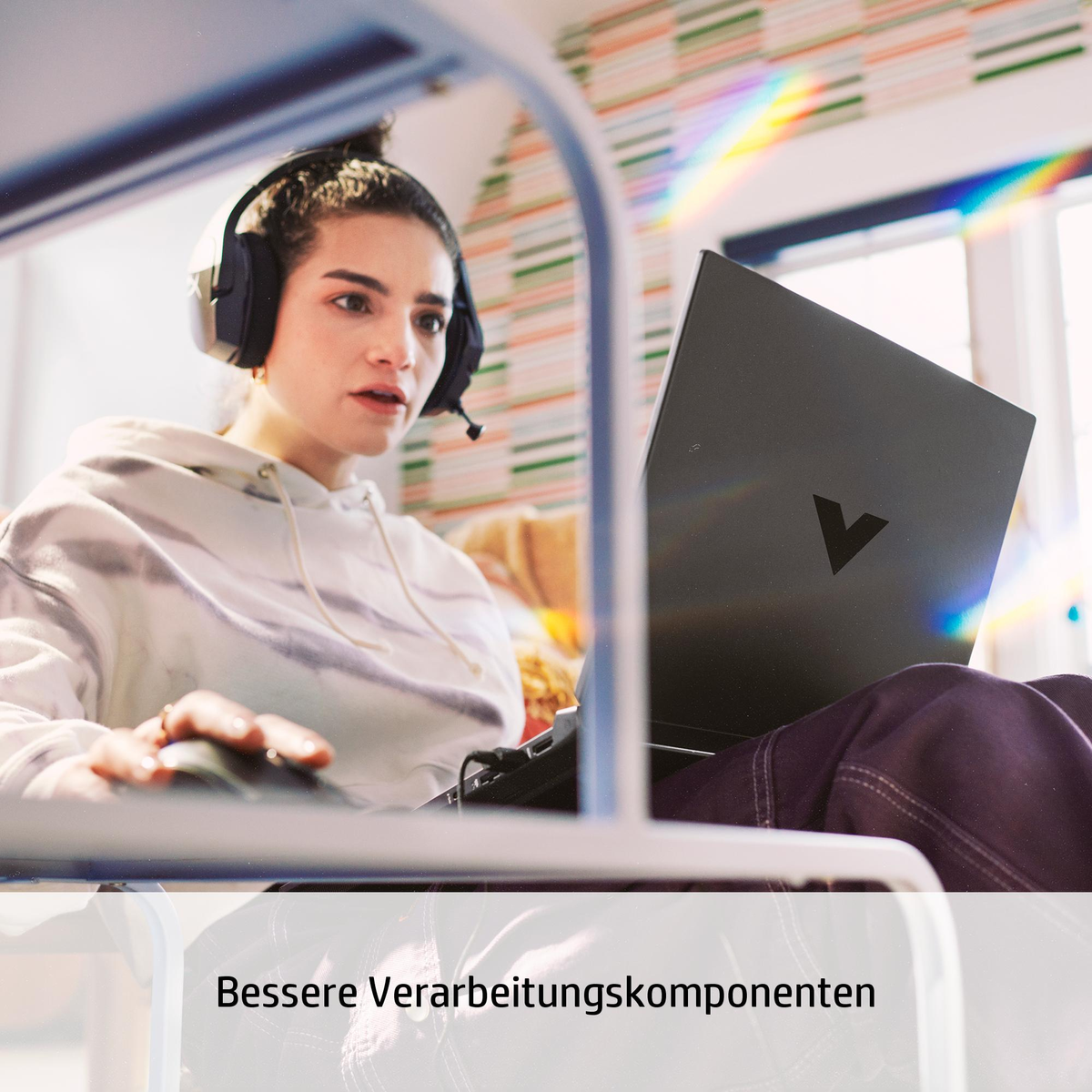 Eine Frau mit Kopfhörern benutzt einen Laptop, mit einem Regenbogeneffekt an der Wand.
