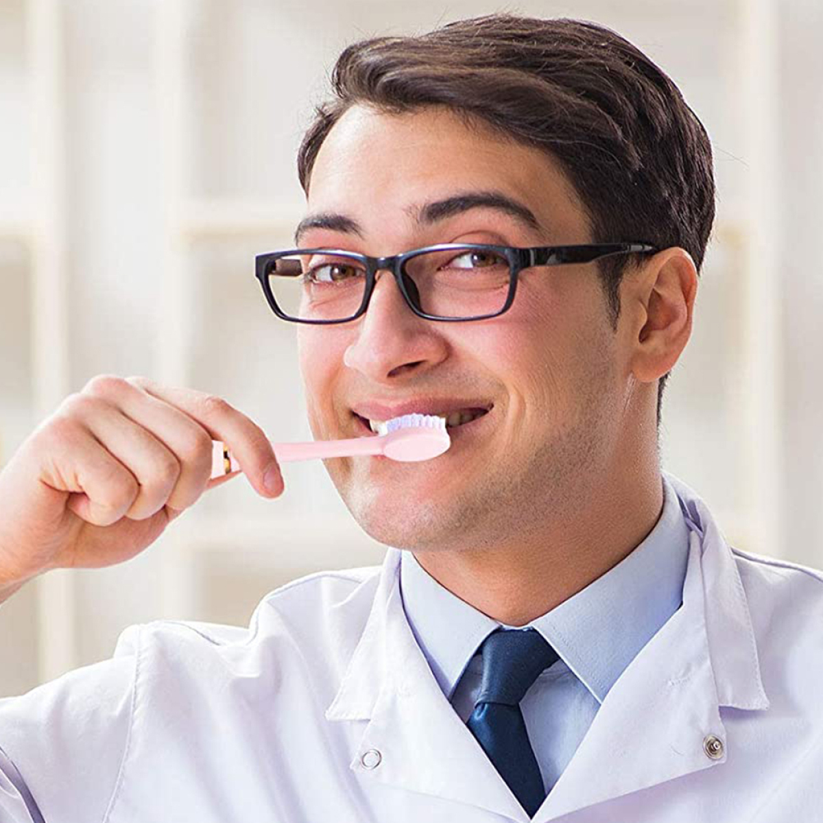 Ein Mann mit Brille putzt sich mit einer rosa Zahnbürste die Zähne.