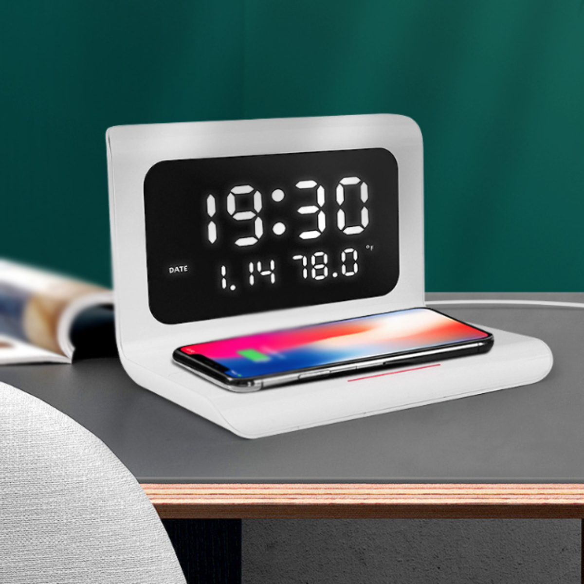 Weißer Digitalwecker mit Telefon auf Ladepad, zeigt Zeit und Temperatur an.