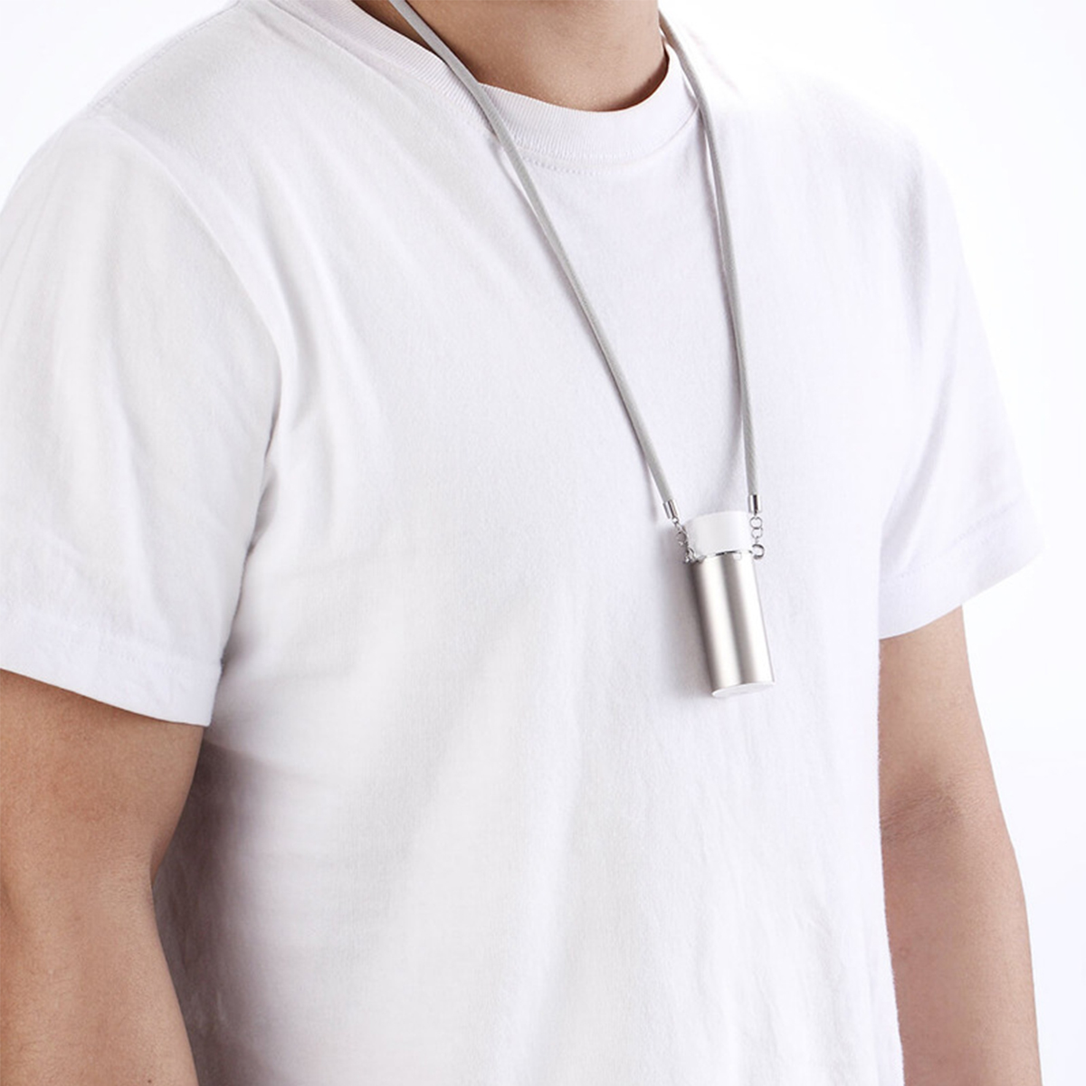 Person trägt ein weißes T-Shirt mit einem silbernen, am Hals getragenen Gerät. Graues Kabel sichtbar.