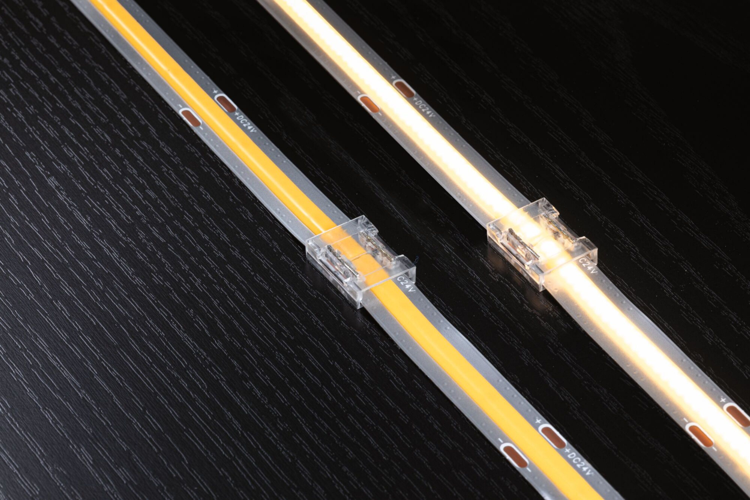 Dwa paski świetlne LED ze złączami, na ciemnej, teksturowanej powierzchni.