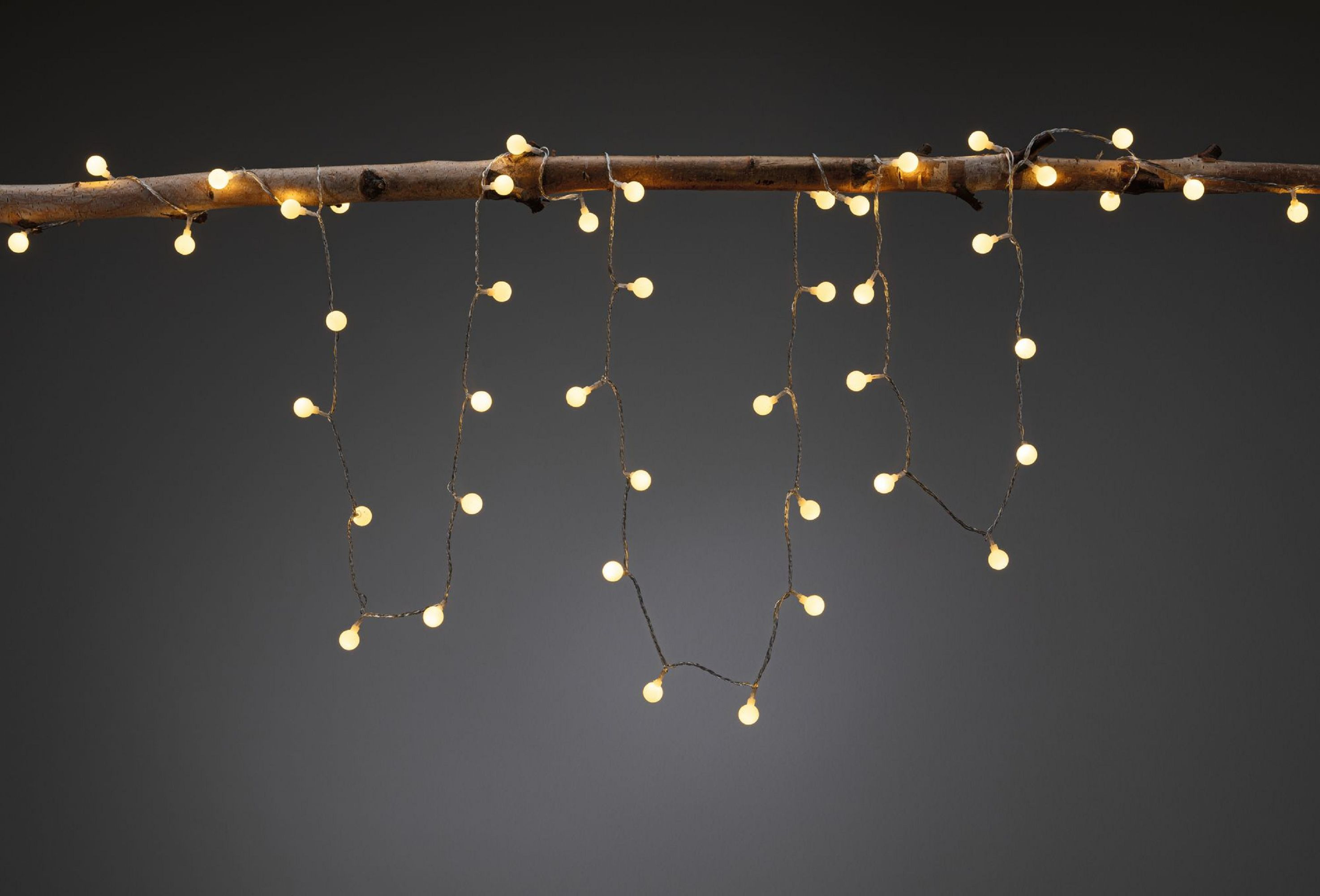 Światła sznurkowe z małymi białymi żarówkami wiszącymi na gałęzi.