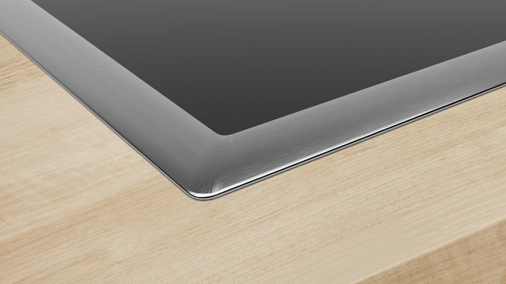 Zbliżenie blatu. Ciemna powierzchnia otoczona jest krawędzią ze stali nierdzewnej.