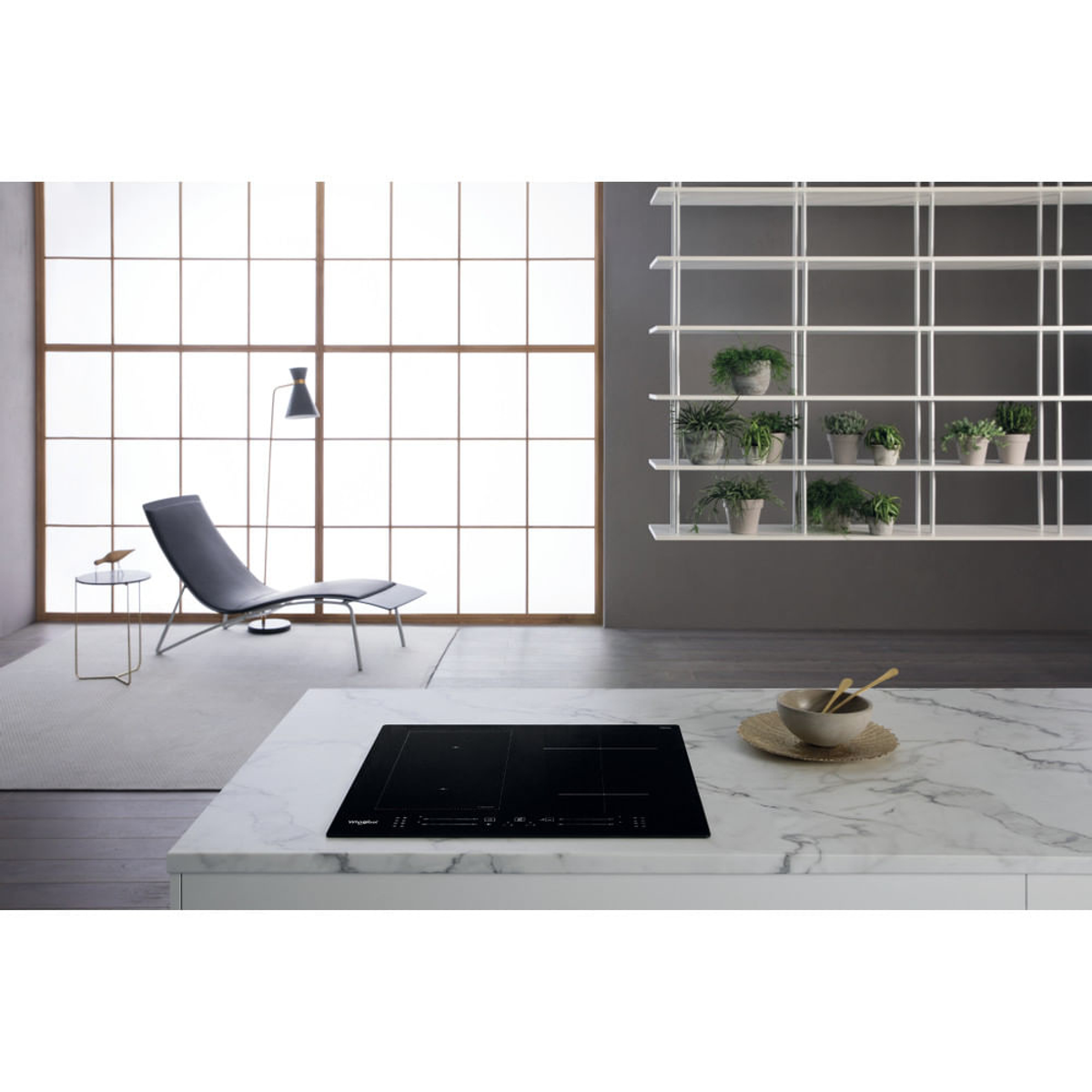 Cucina moderna con piano in marmo, piano cottura nero, poltrona, finestra, mensole con piante.