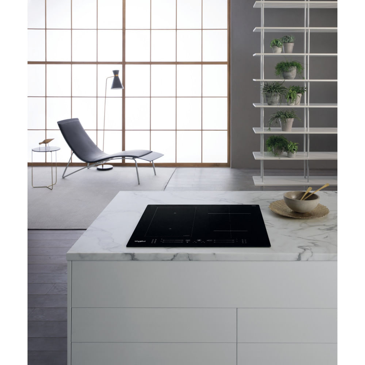 Piano cottura a induzione nero su un piano di lavoro in marmo bianco in una cucina moderna.