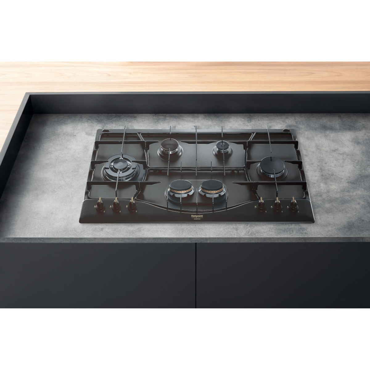 Czarna płyta grzewcza wbudowana w blat, z palnikami gazowymi i pokrętłami.