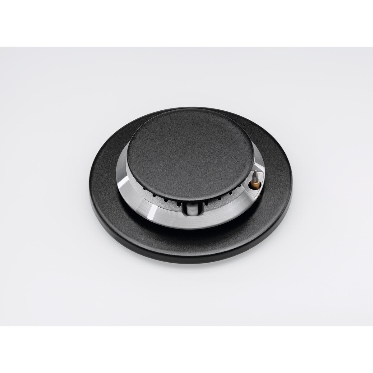 Zbliżenie czarnego palnika kuchenki i otaczającej czarnej powierzchni na białym tle.