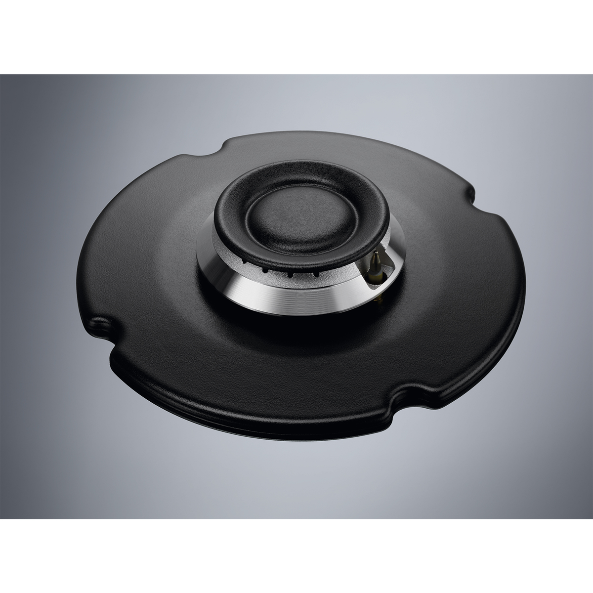 Czarny palnik kuchenki z czarną podstawą i srebrnym pierścieniem. Szare tło. Zbliżenie.