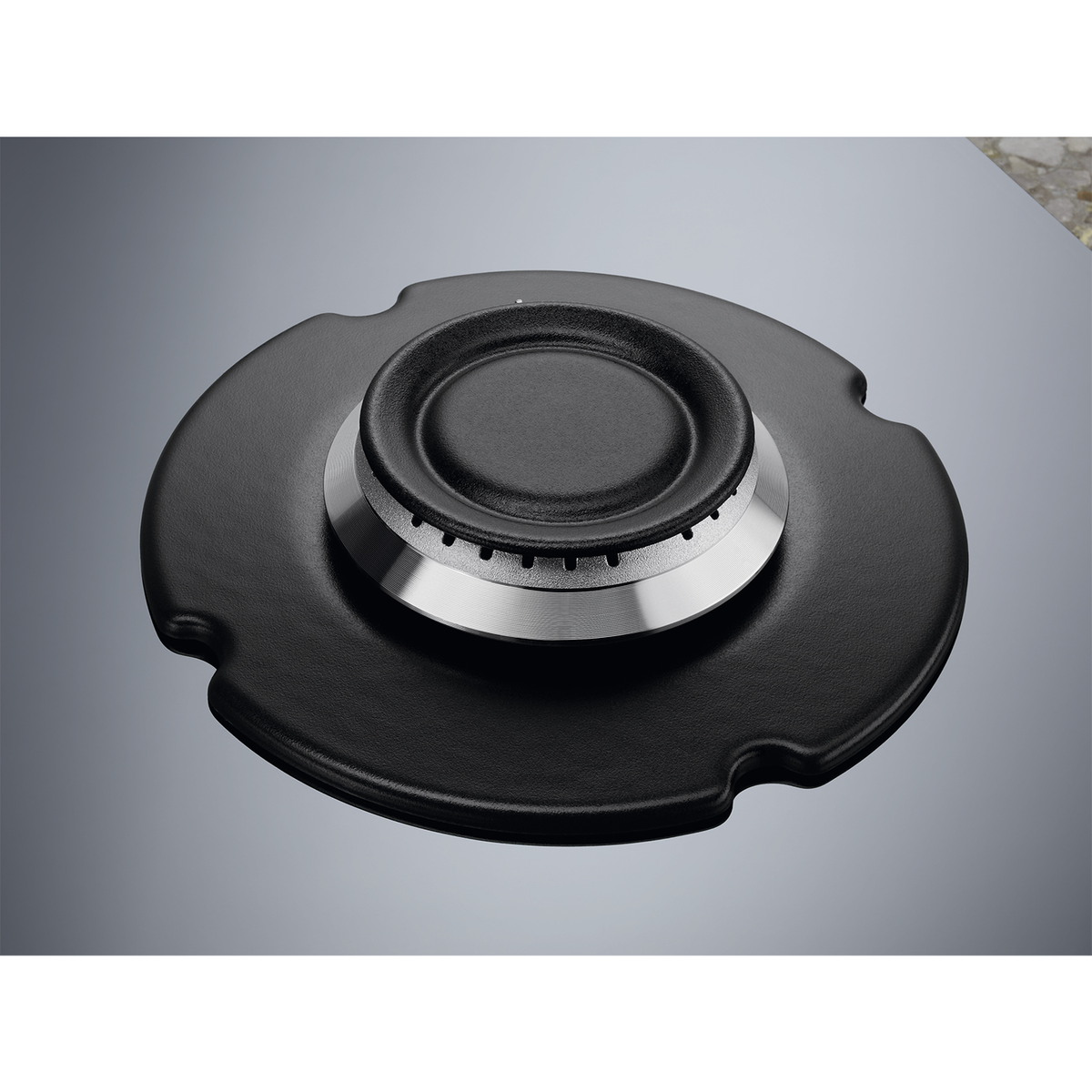 Zbliżenie czarnego palnika gazowego na szarej powierzchni.