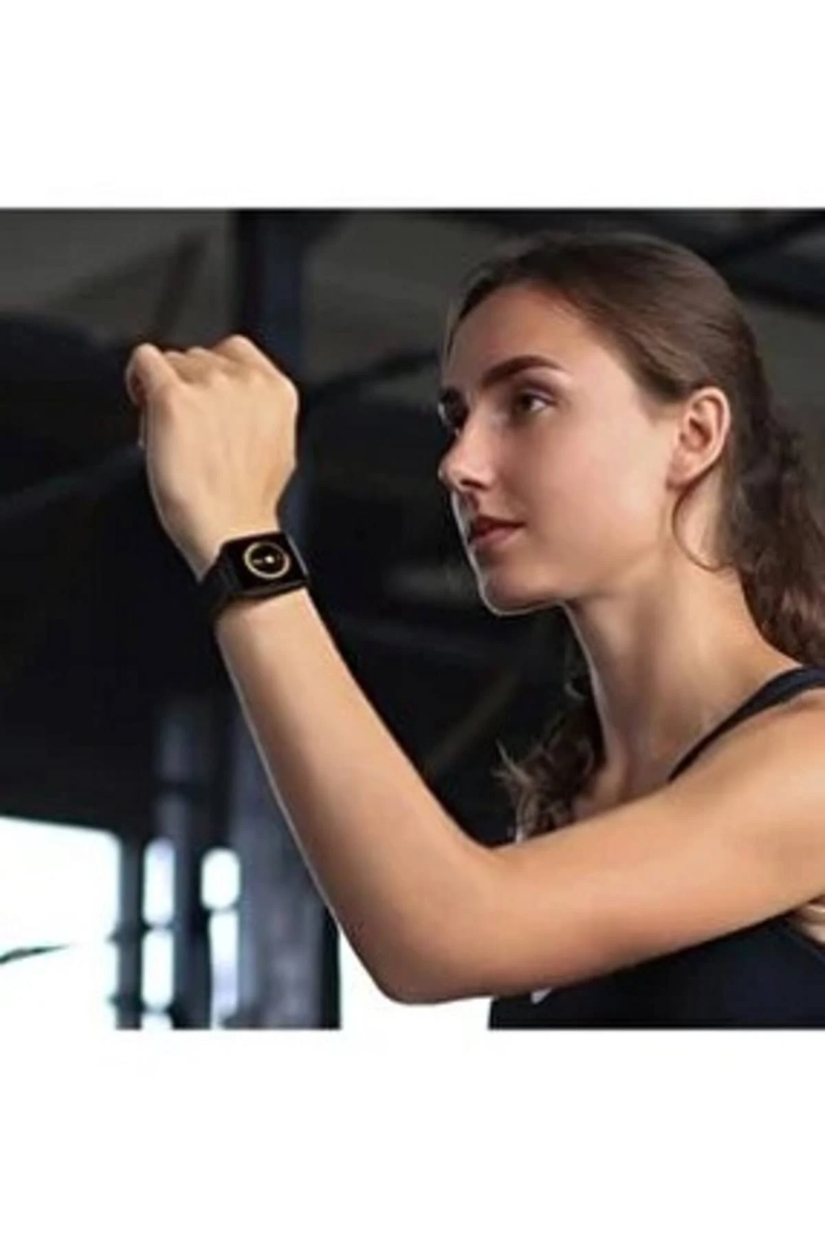 Frau mit schwarzer Smartwatch, Arm gehoben. Hintergrund ist eine verschwommene Inneneinstellung.
