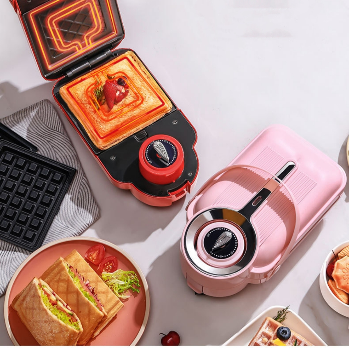 Roter und rosa Sandwichmaker mit Sandwich. Auch anderes Essen und rosa Gerät.