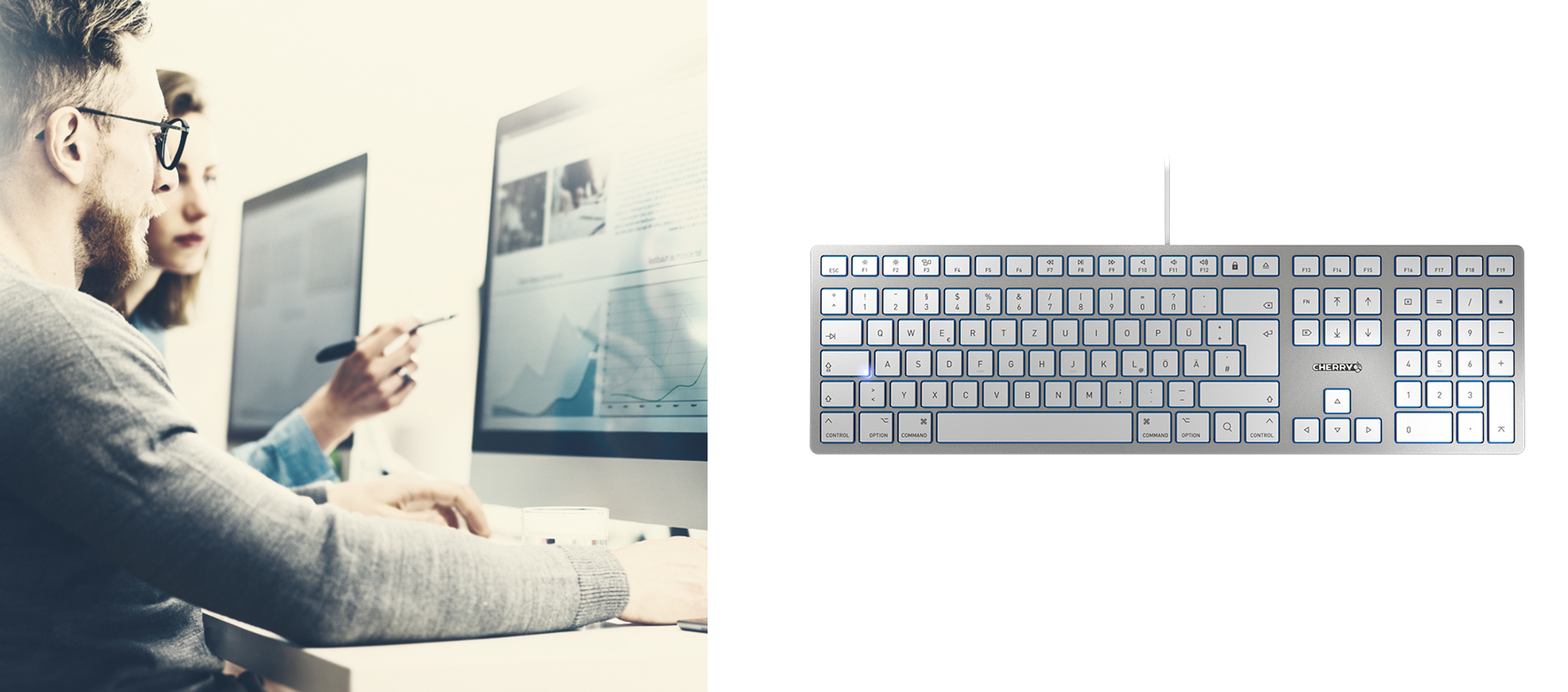Zwei Personen arbeiten an einem Computer, rechts eine Tastatur. Die Tastatur hat Hintergrundbeleuchtung.