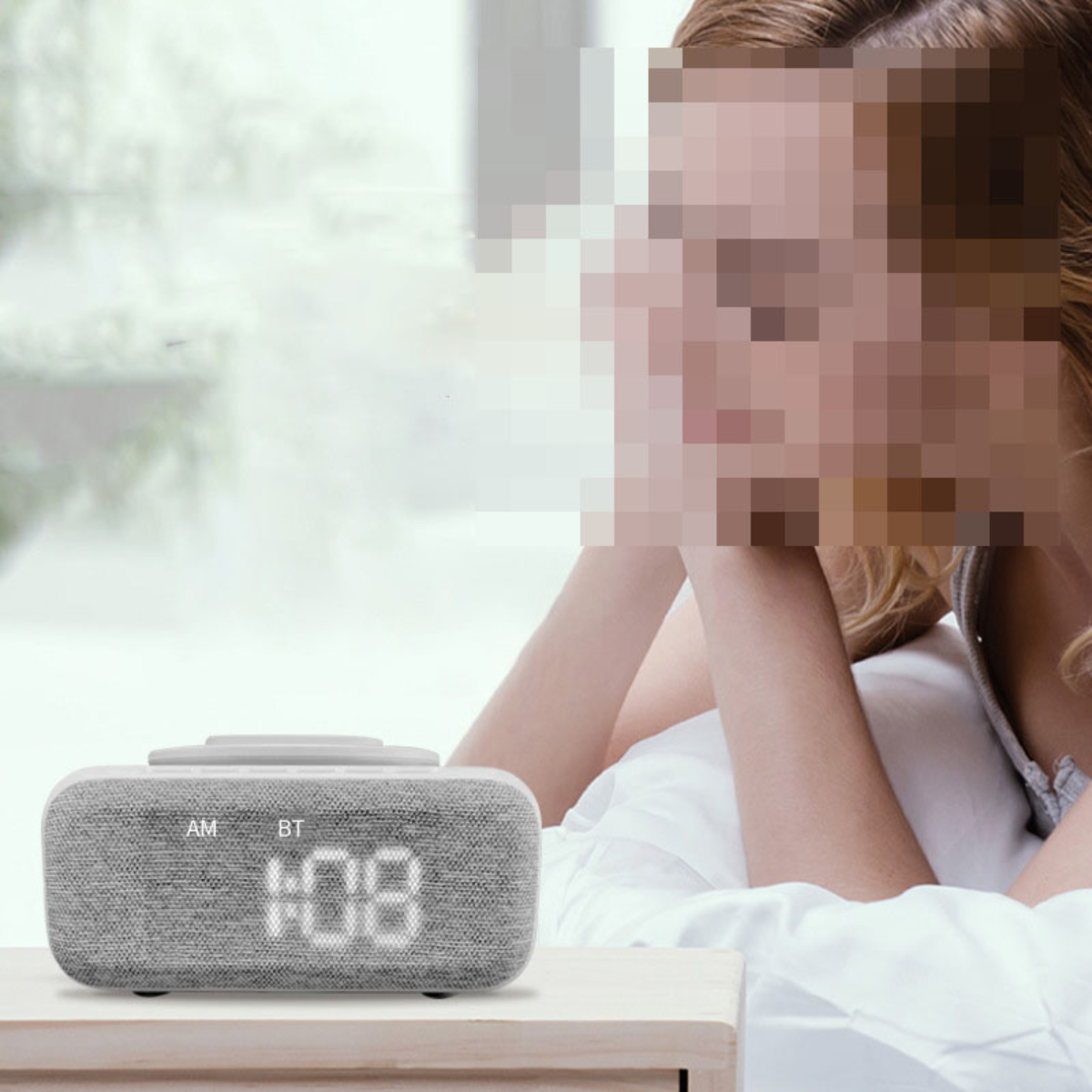 Wecker auf einem Nachttisch; Frau im Bett im Hintergrund, Gesicht verschwommen.