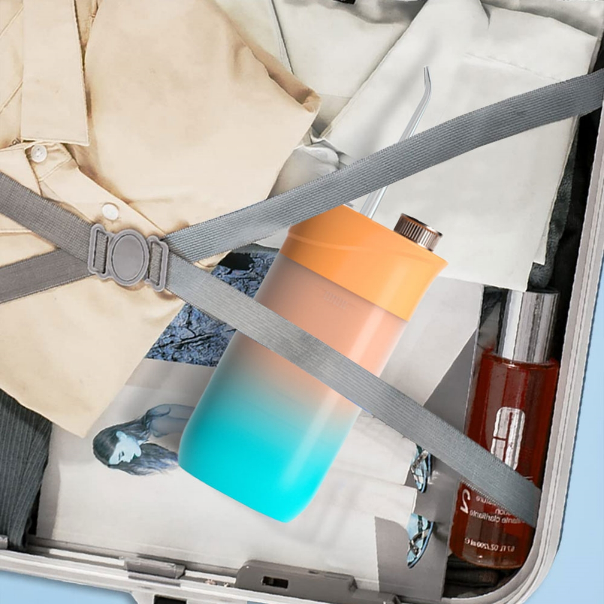 Ein Koffer ist geöffnet mit Kleidung, einer Wasserflasche und Schönheitsprodukten im Inneren, gehalten von einem grauen Gurt.