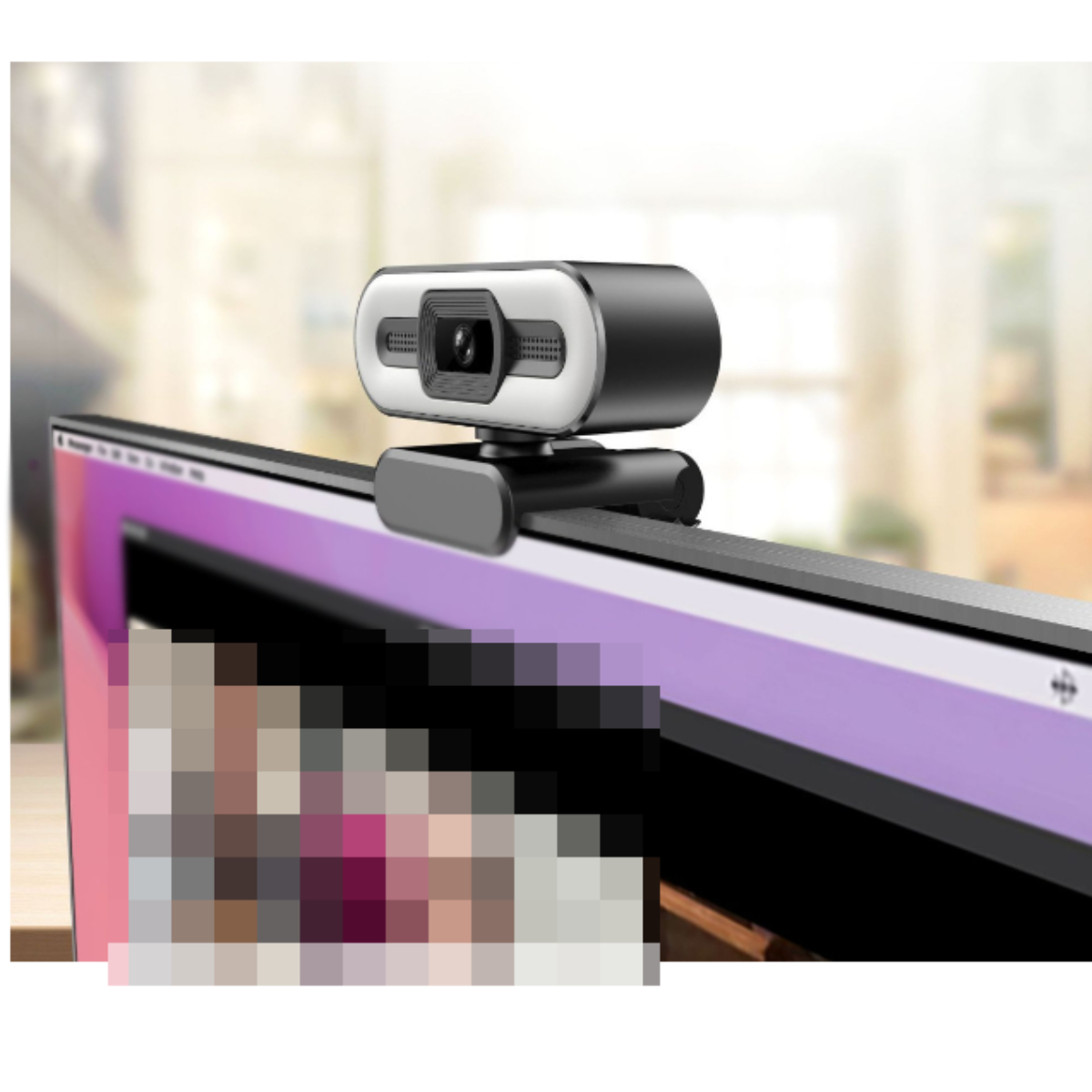 Eine schwarze Webcam sitzt auf einem Monitor. Verschwommener Hintergrund zeigt ein Büro. Die Webcam ist silber und schwarz.