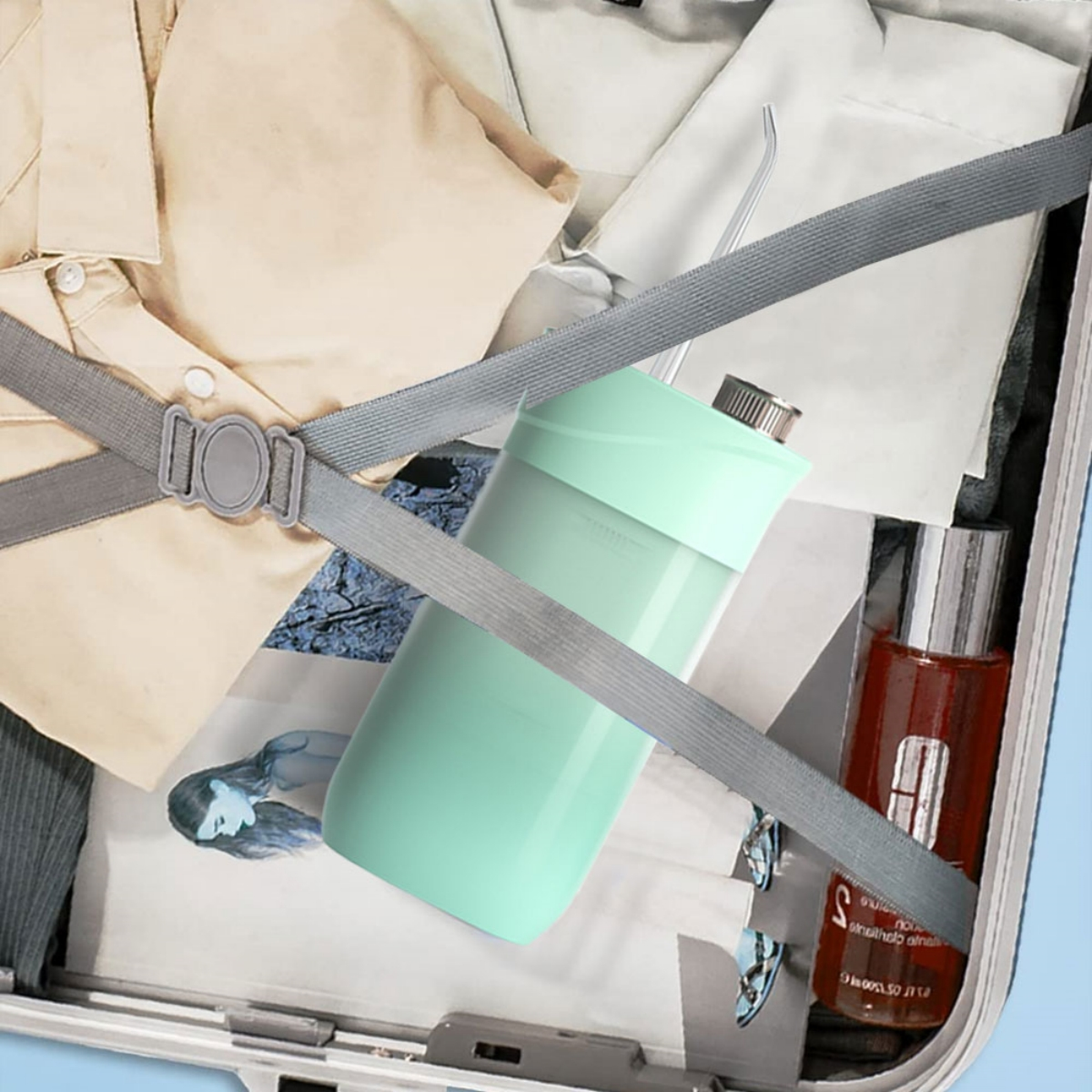 Ein Koffer mit Kleidung und einer Wasserflasche im Inneren, mit einem Gurt.