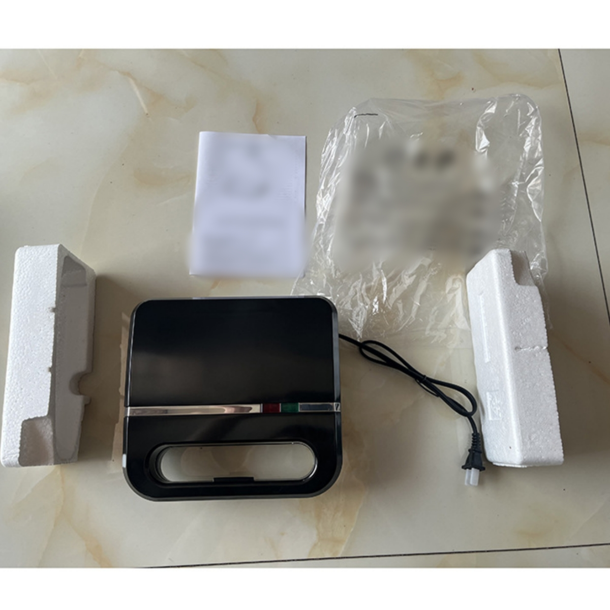 Schwarzer Sandwichmaker mit Zubehör und Verpackung.