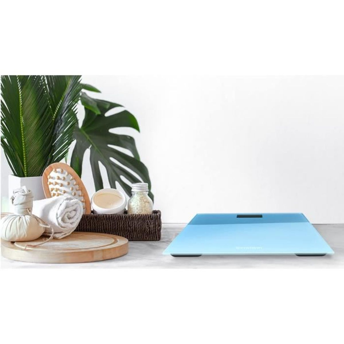 Scena łazienkowa z wagą, ręcznikami, szczotką i roślinami. Nowoczesna, jasnoniebieska waga na marmurze.