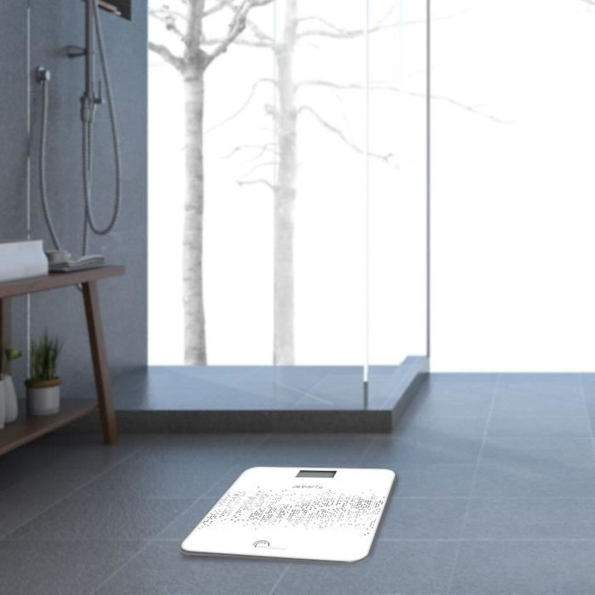 Łazienka z białą wagą. Szara podłoga, duże okno z drzewami na zewnątrz. Widoczny prysznic.