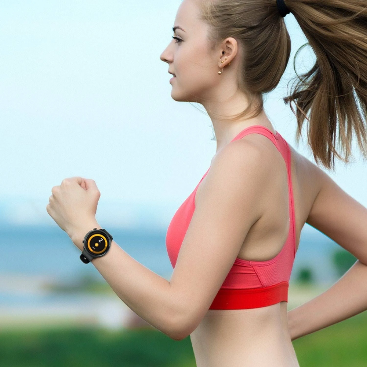 Una donna che corre con uno smartwatch al polso. L'orologio è nero con un cinturino arancione.