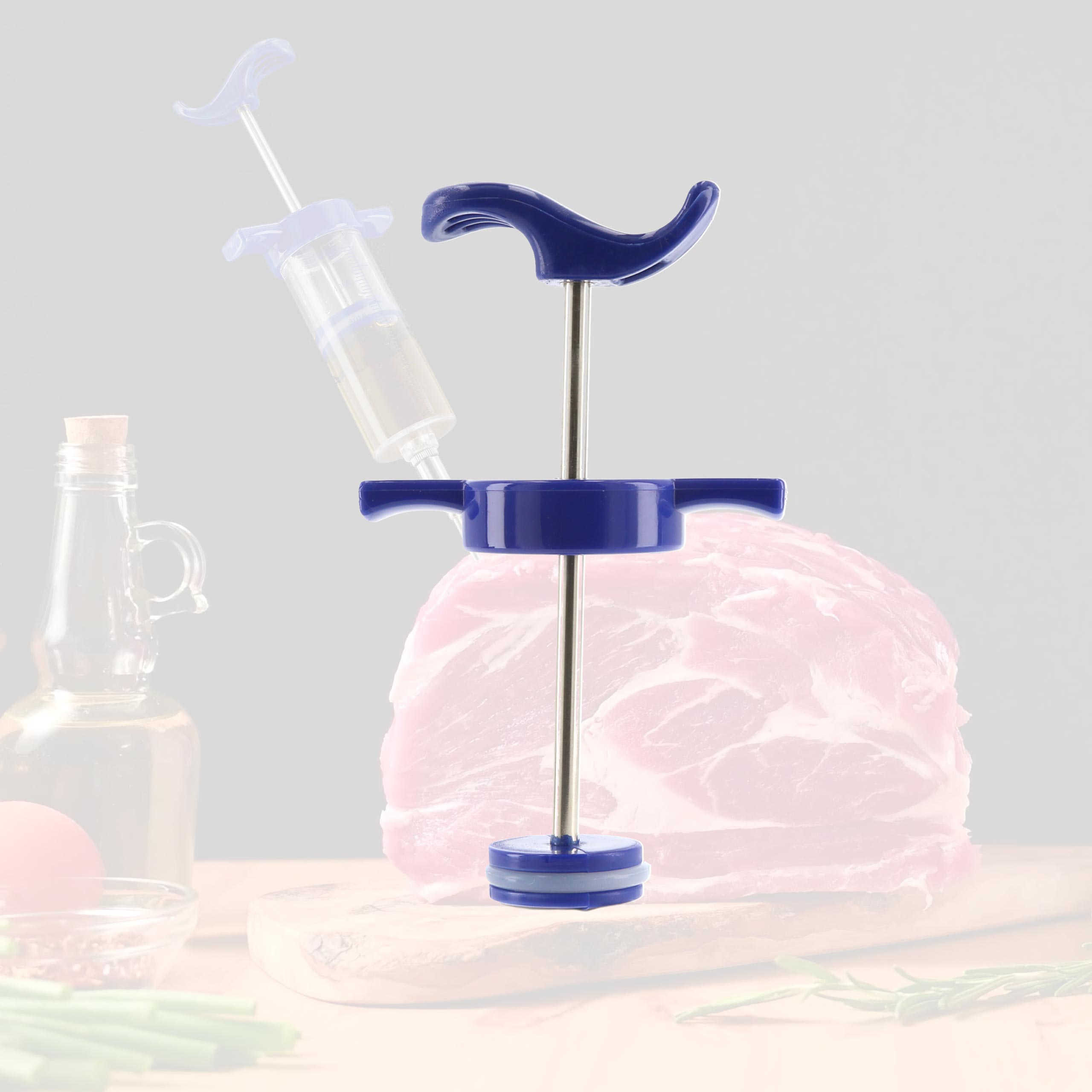 Fleischinjektor über einem Fleischstück. Eine Flasche und etwas Gemüse im Hintergrund.