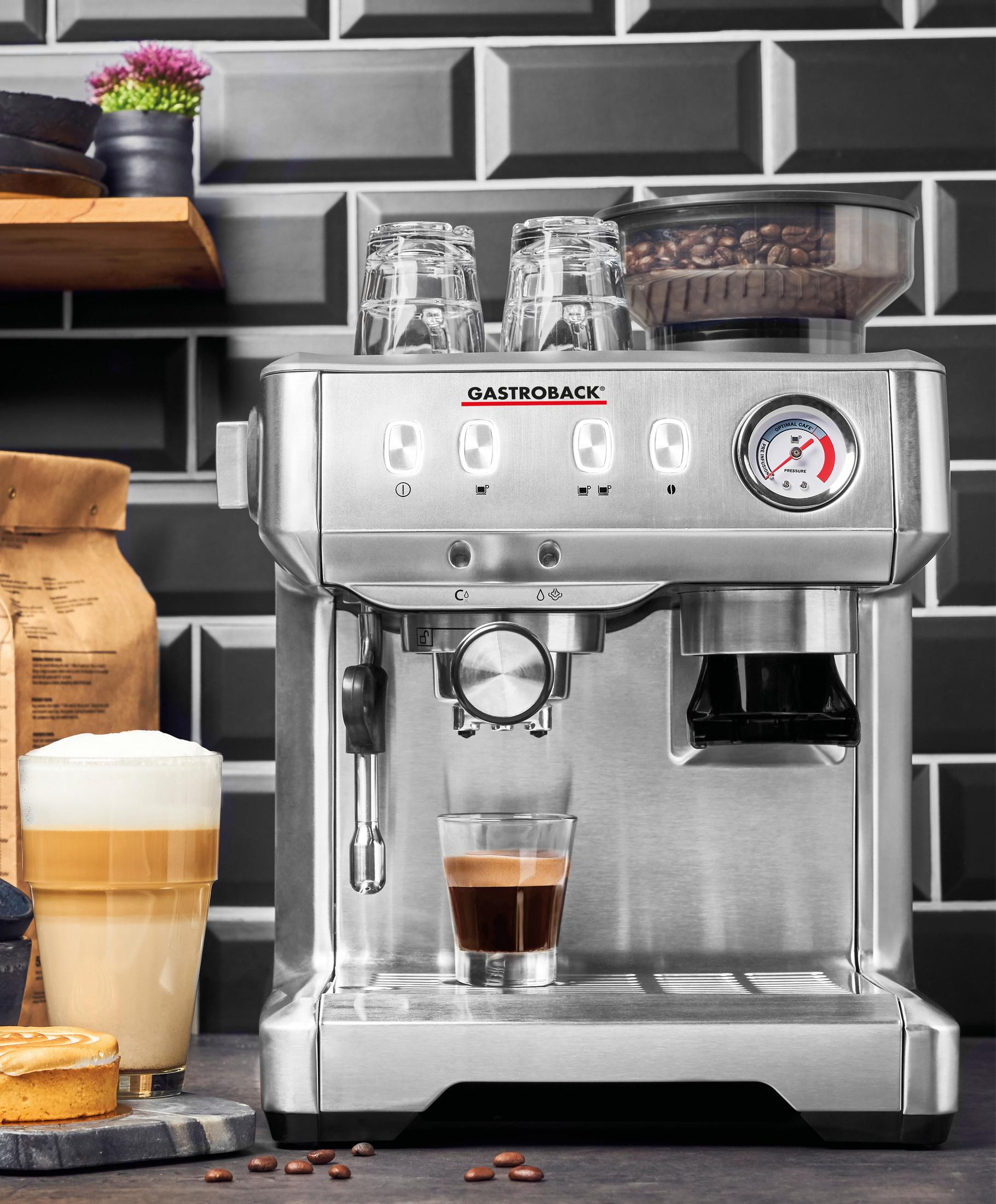 Ekspres do espresso ze stali nierdzewnej ze szklanką latte i espresso. Czarne tło z płytek.