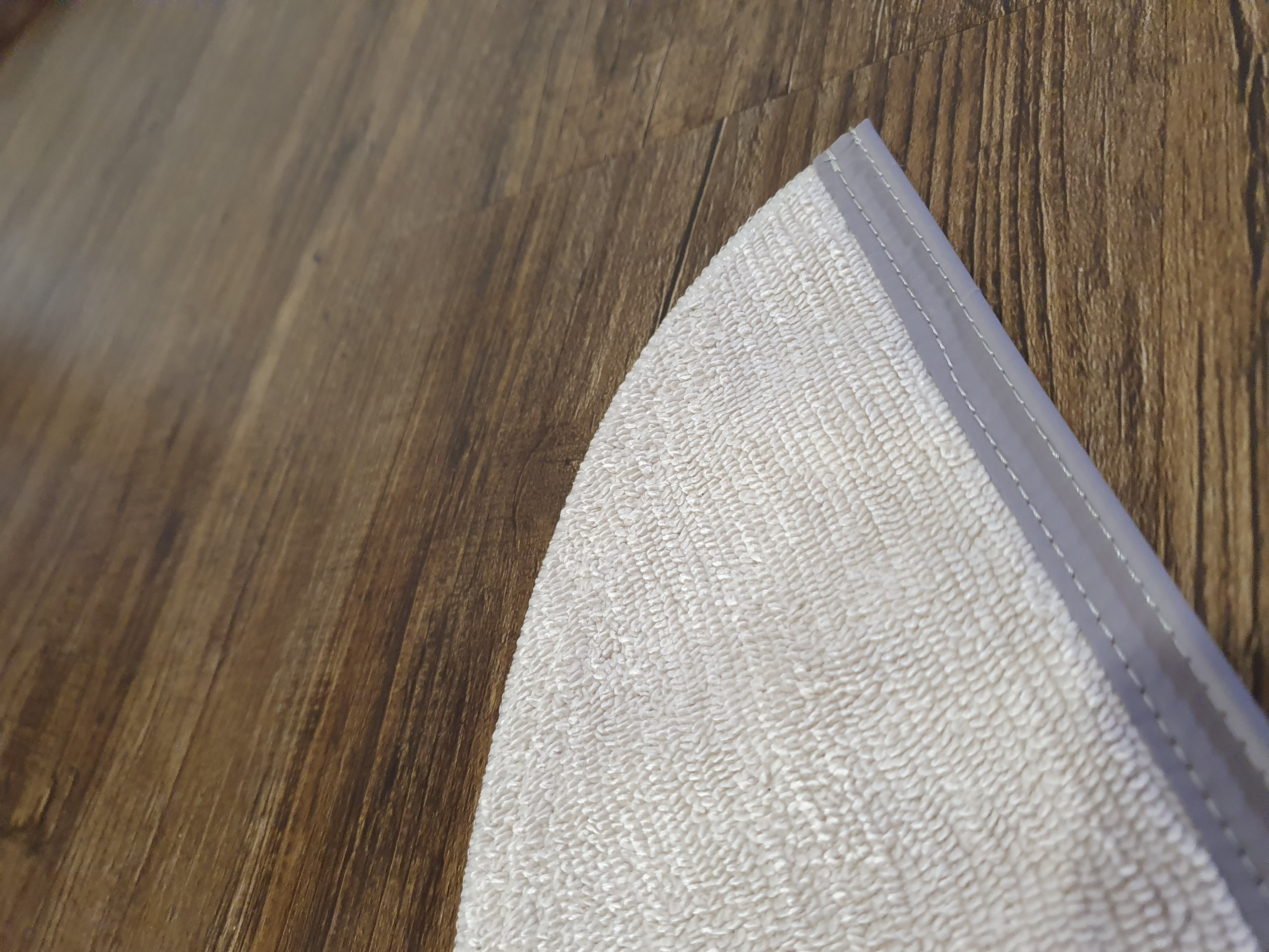 Asciugamano bianco su pavimento in legno, mostra un angolo e trama.