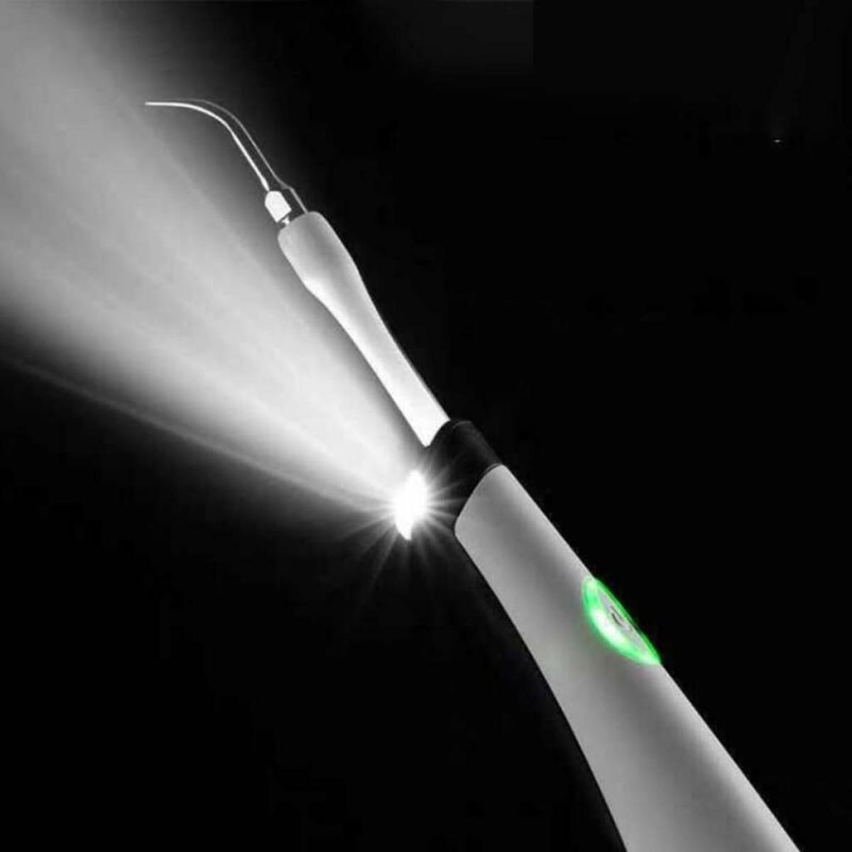 Zahnreinigungswerkzeug mit hellem Licht, verwendet vor schwarzem Hintergrund.