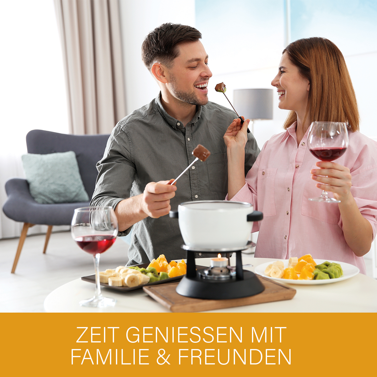 Para delektująca się fondue; mężczyzna karmi kobietę kawałkiem czekolady. Stół z owocami i kieliszkami.