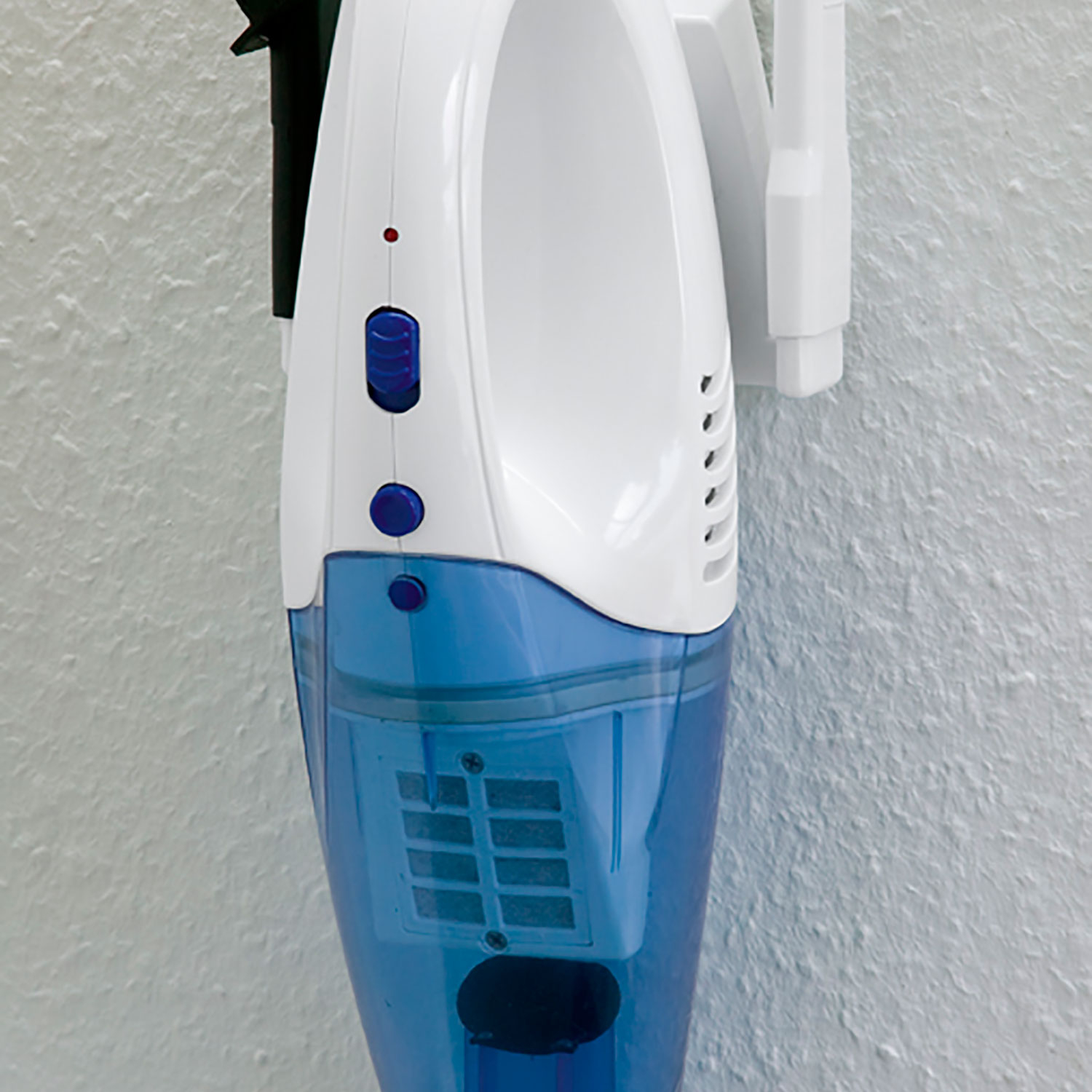 Biało-niebieski odkurzacz ręczny zamontowany na ścianie. Posiada dwa przyciski i port ładowania.