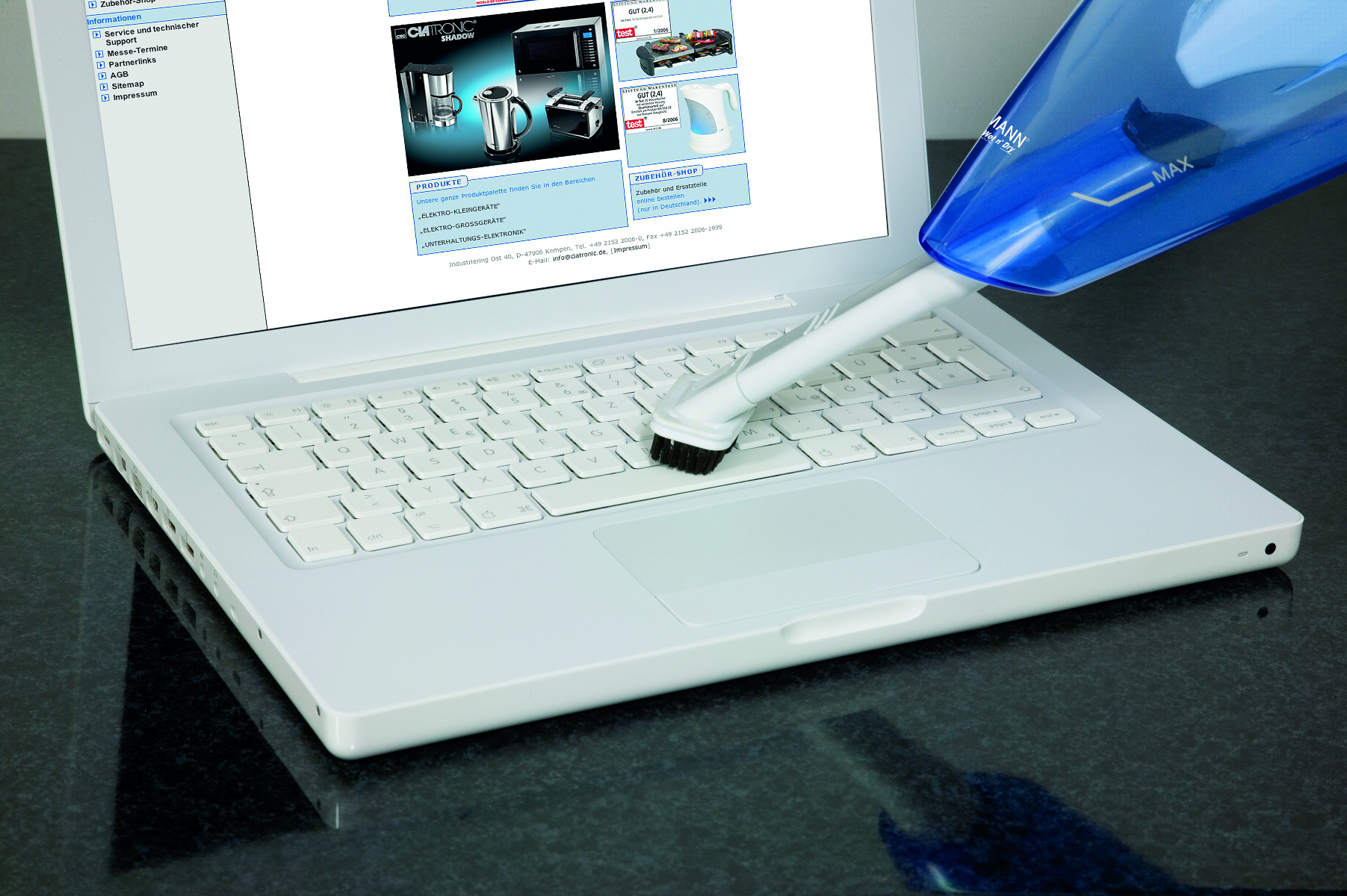 Odkurzacz ręczny czyszczący białą klawiaturę laptopa. Na ekranie sklep internetowy.