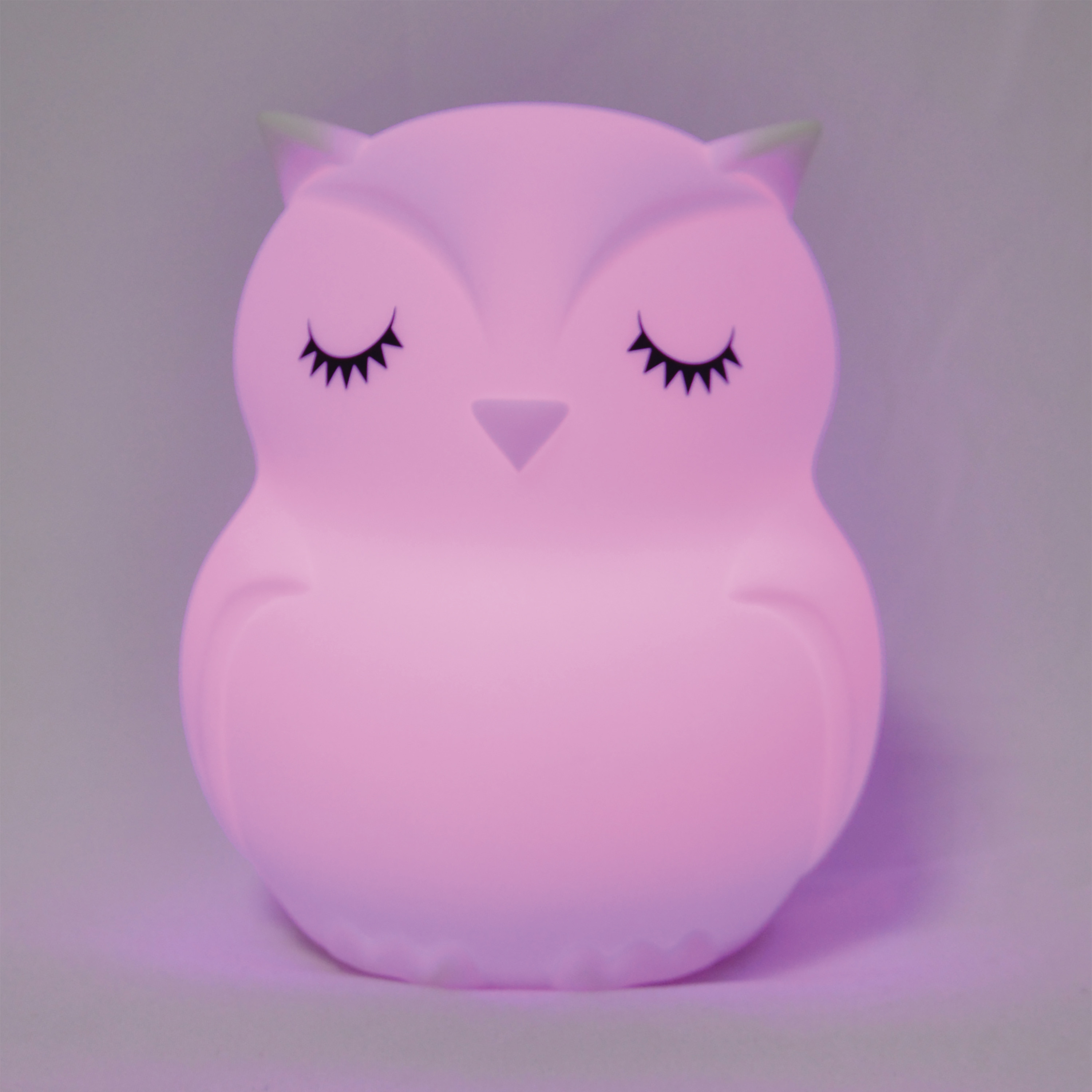 Una luz nocturna rosa con forma de búho con los ojos cerrados.