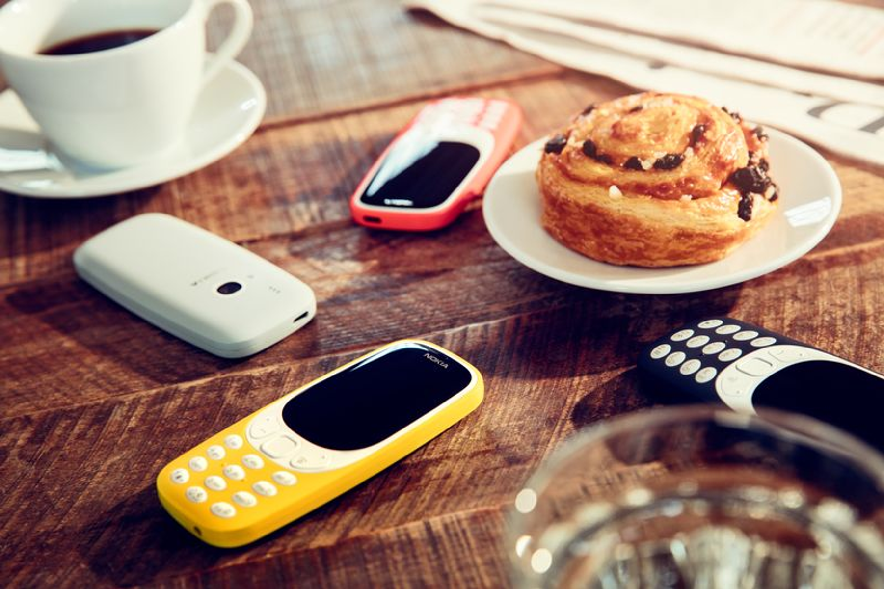 Stół z telefonami, kawą i ciastkami. Telefony są żółte, czerwone i białe.