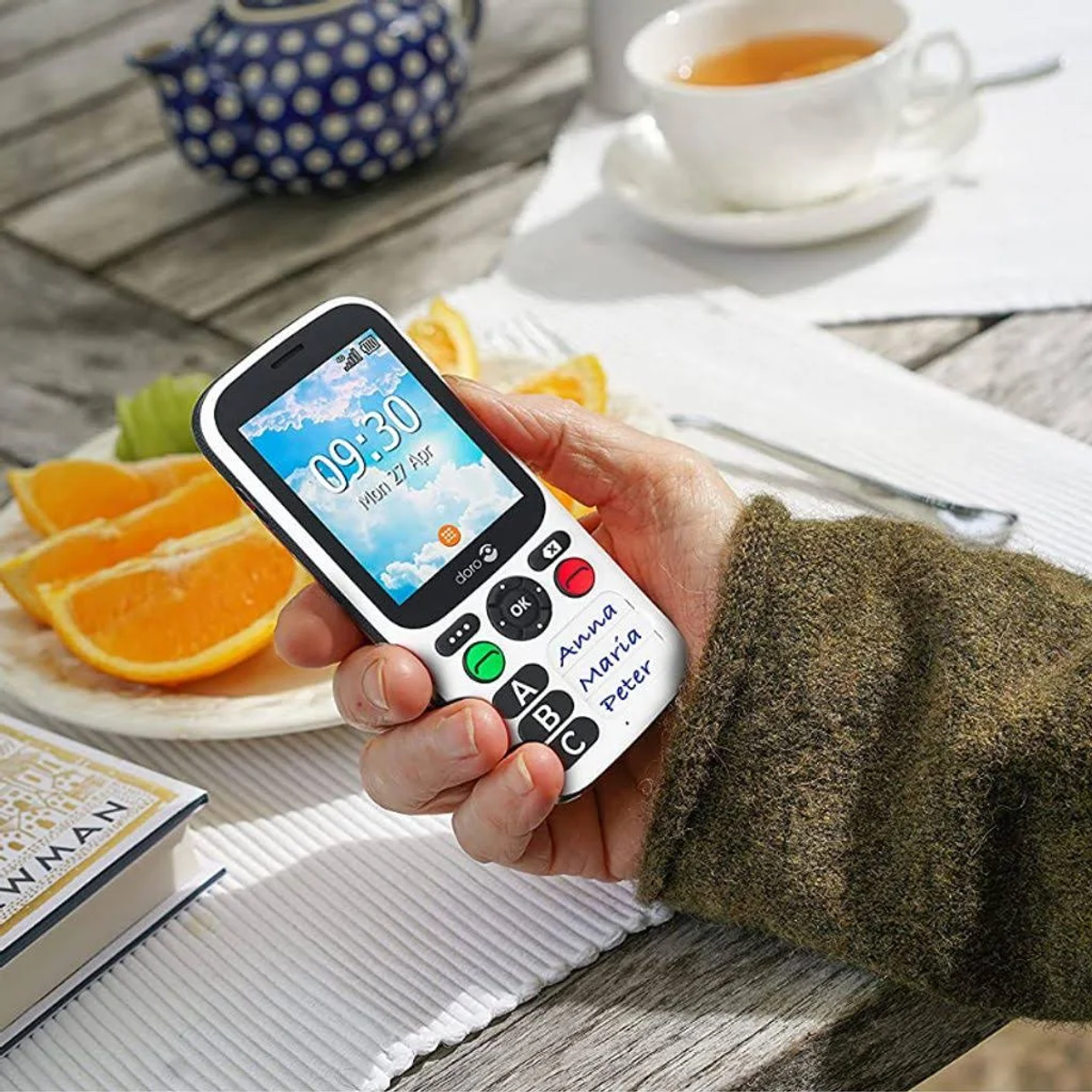 Una mano sosteniendo un teléfono blanco con una pantalla que muestra un calendario.