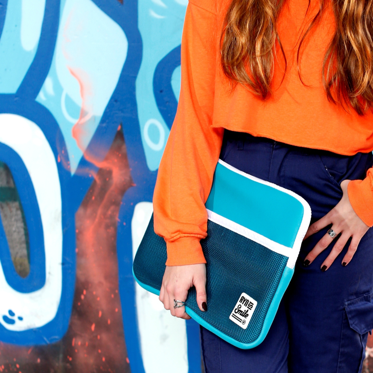 Una persona sostiene una funda azul para portátil con diseño blanco y turquesa.