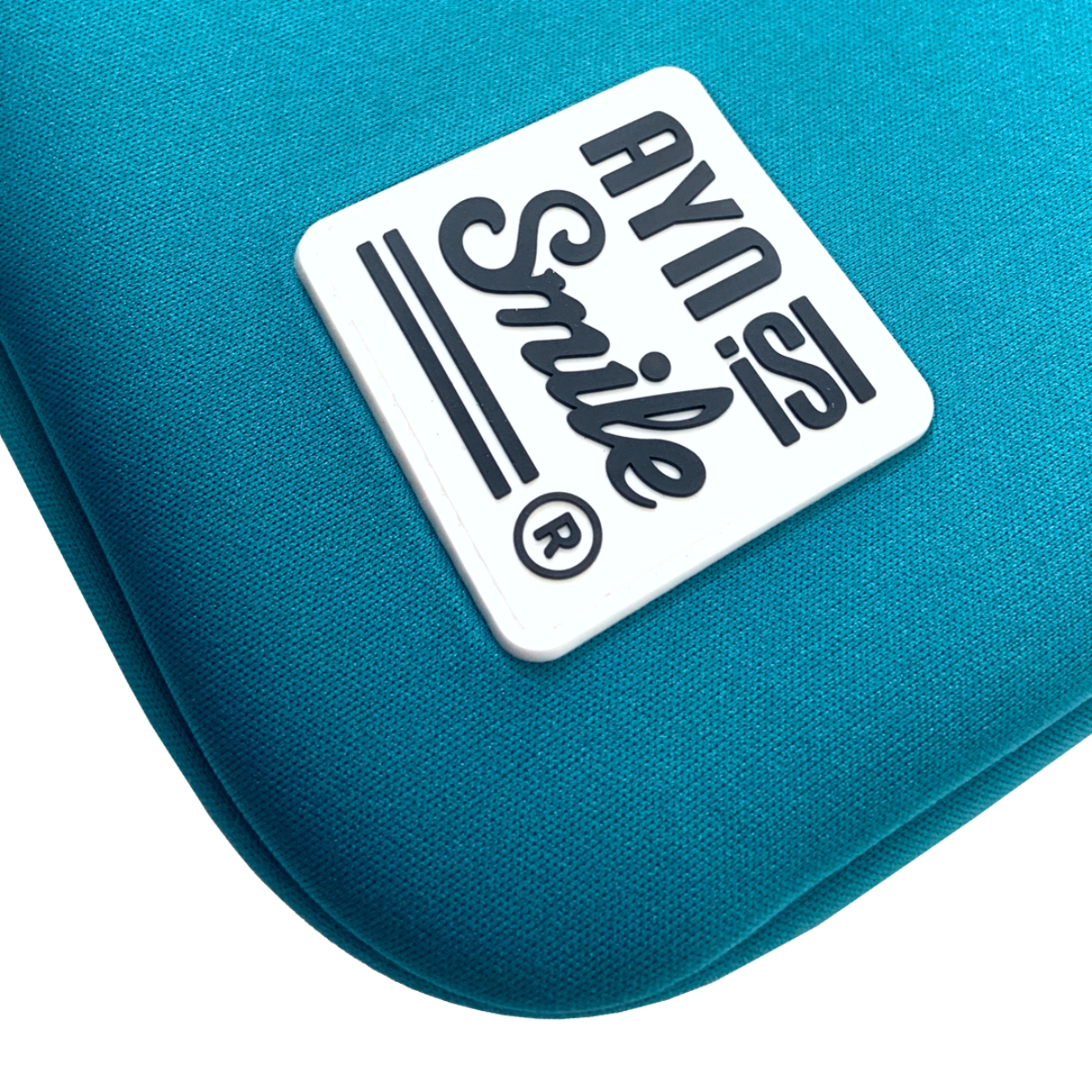 Primer plano de una funda turquesa con un logo blanco que dice 'Ayn is Smile'.