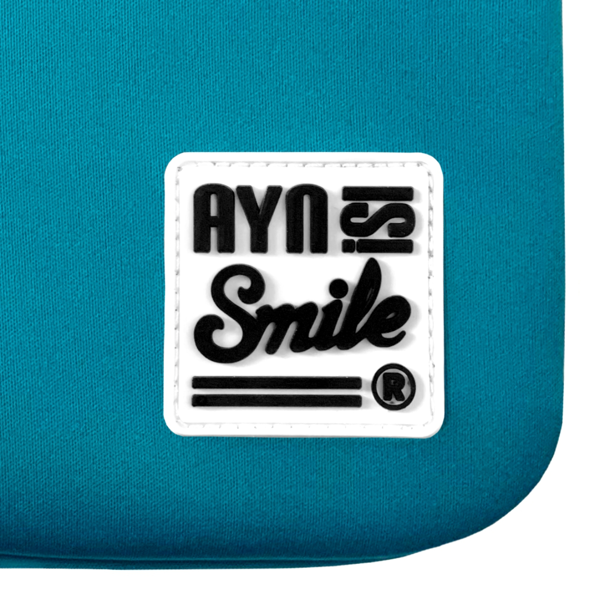 Un logotipo blanco sobre una tela azul turquesa. El logotipo dice 'AYN Smile' en una escritura estilizada.