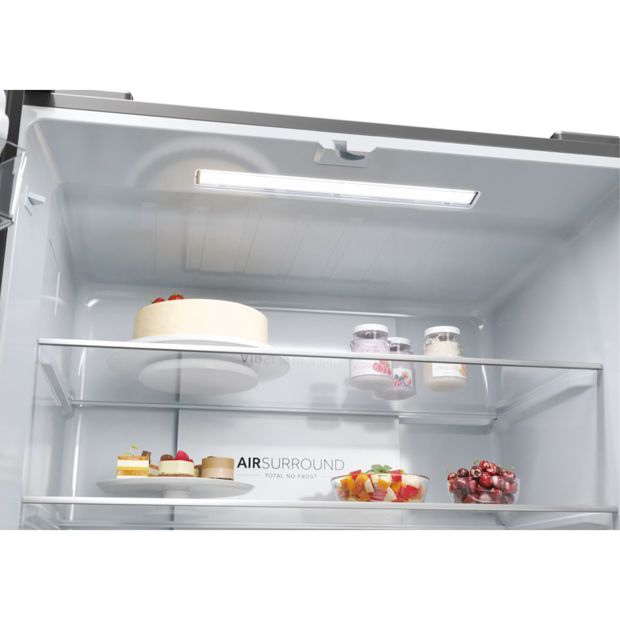Intérieur d'un réfrigérateur. Il y a un gâteau, des bocaux, des fruits et des desserts.