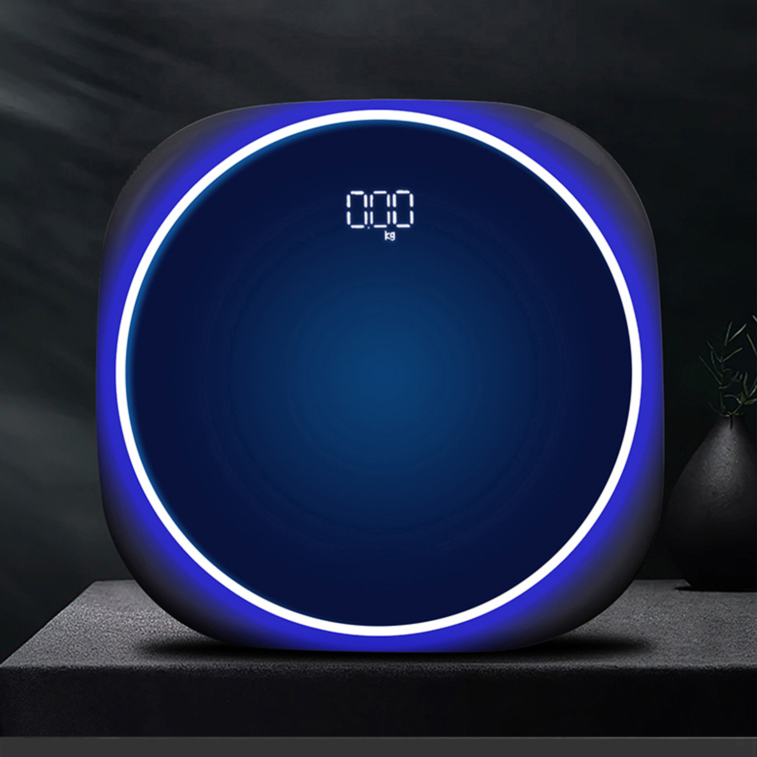 Bilancia da bagno digitale con display blu che mostra '000 kg' su superficie scura.
