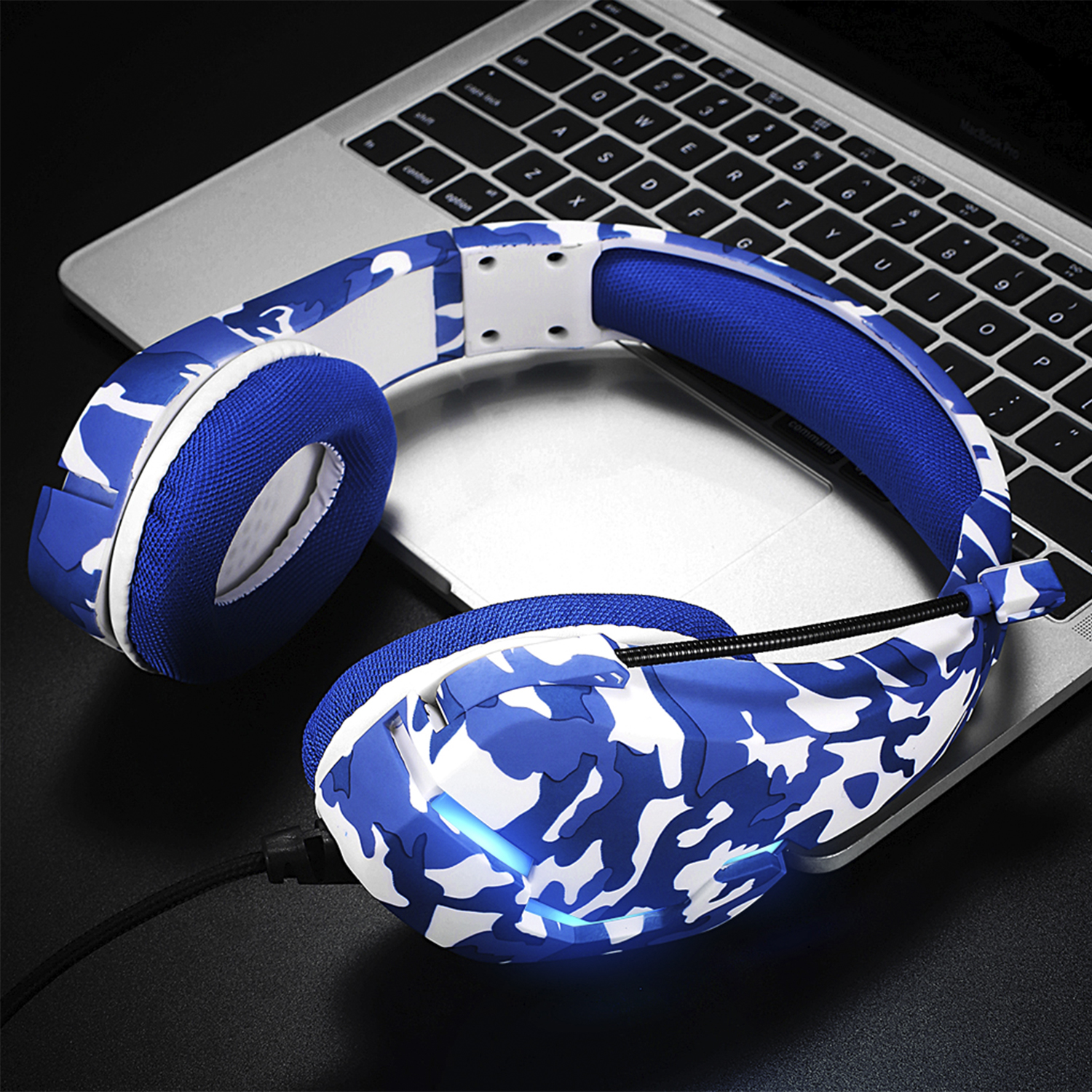 Auriculares de camuflaje azul y blanco en un portátil. Superficie negra.